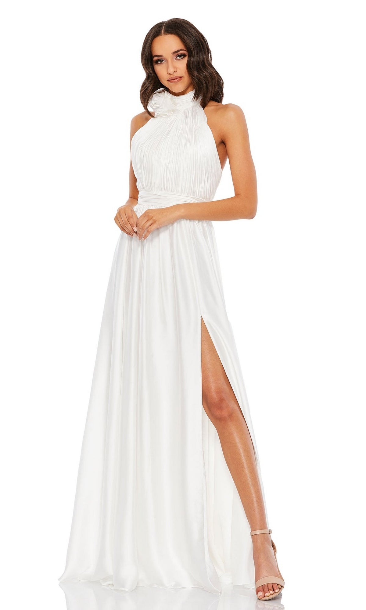 A woman models the Mac Duggal 49333 High-Neck Halter Formal Dress, a sleeveless white gown with a ruched bodice and high slit, standing against a plain white background.