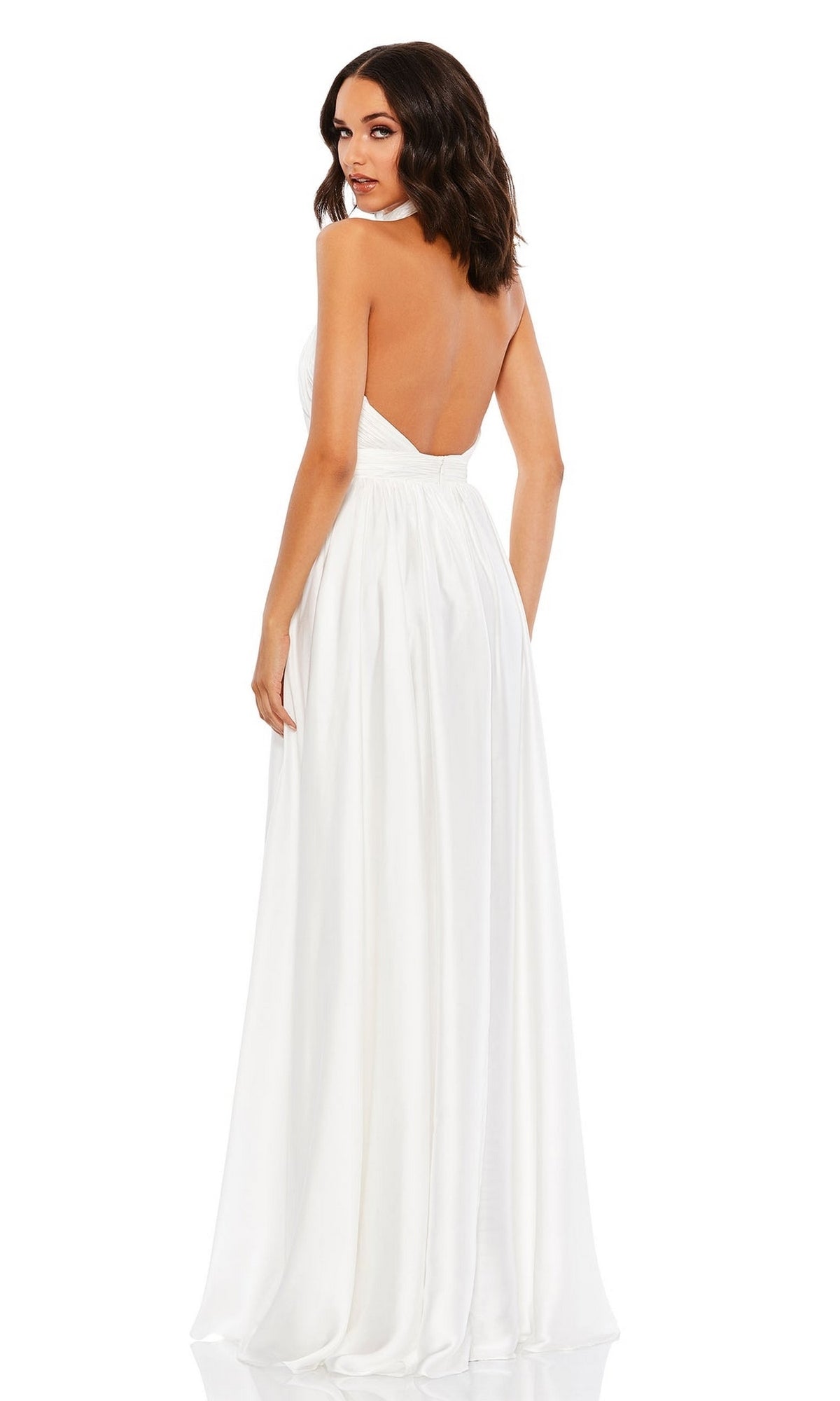 A woman stands against a white background, looking over her shoulder in the High-Neck Halter Formal Dress: Mac Duggal 49333—a floor-length, open-back evening gown.