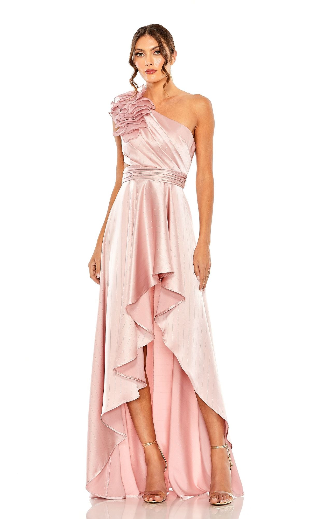 Woman in a light pink Mac Duggal 49523 one-shoulder wedding guest dress with ruffle strap and asymmetrical layered hem, paired with strappy high heels—a chic party-ready look.