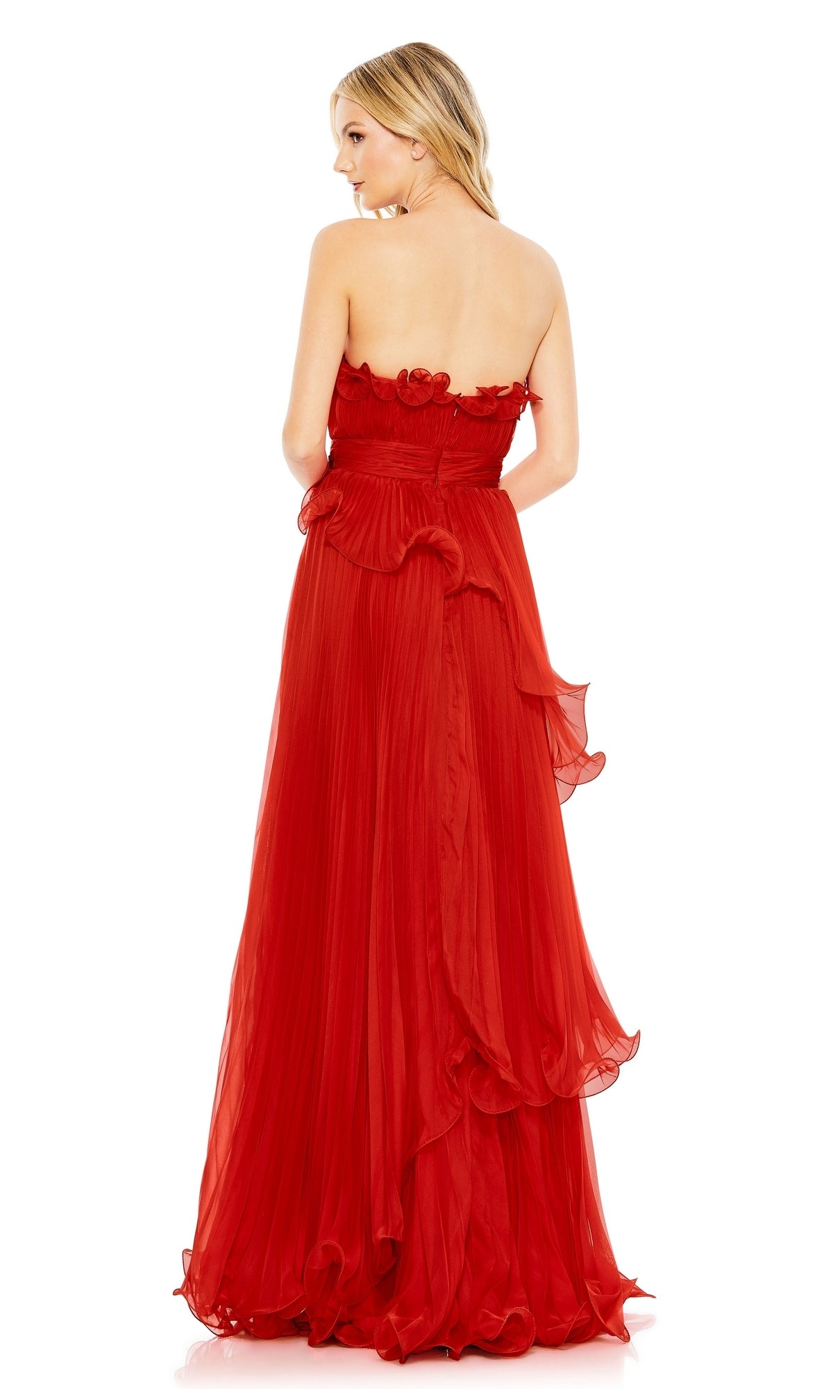 A woman wearing the Long Formal Dress 49537 by Mac Duggal, a strapless, floor-length red gown with an empire waist, pleated skirt, and ruffled details, stands facing away from the camera.