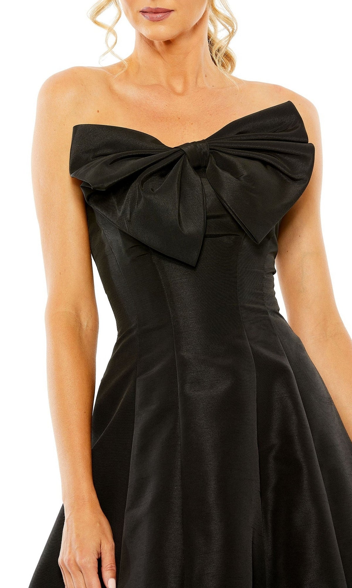 A woman wears the Mac Duggal 49605 Tea-Length Wedding-Guest Dress, a strapless black style with a large bow at the chest—ideal for a simple wedding-guest look.