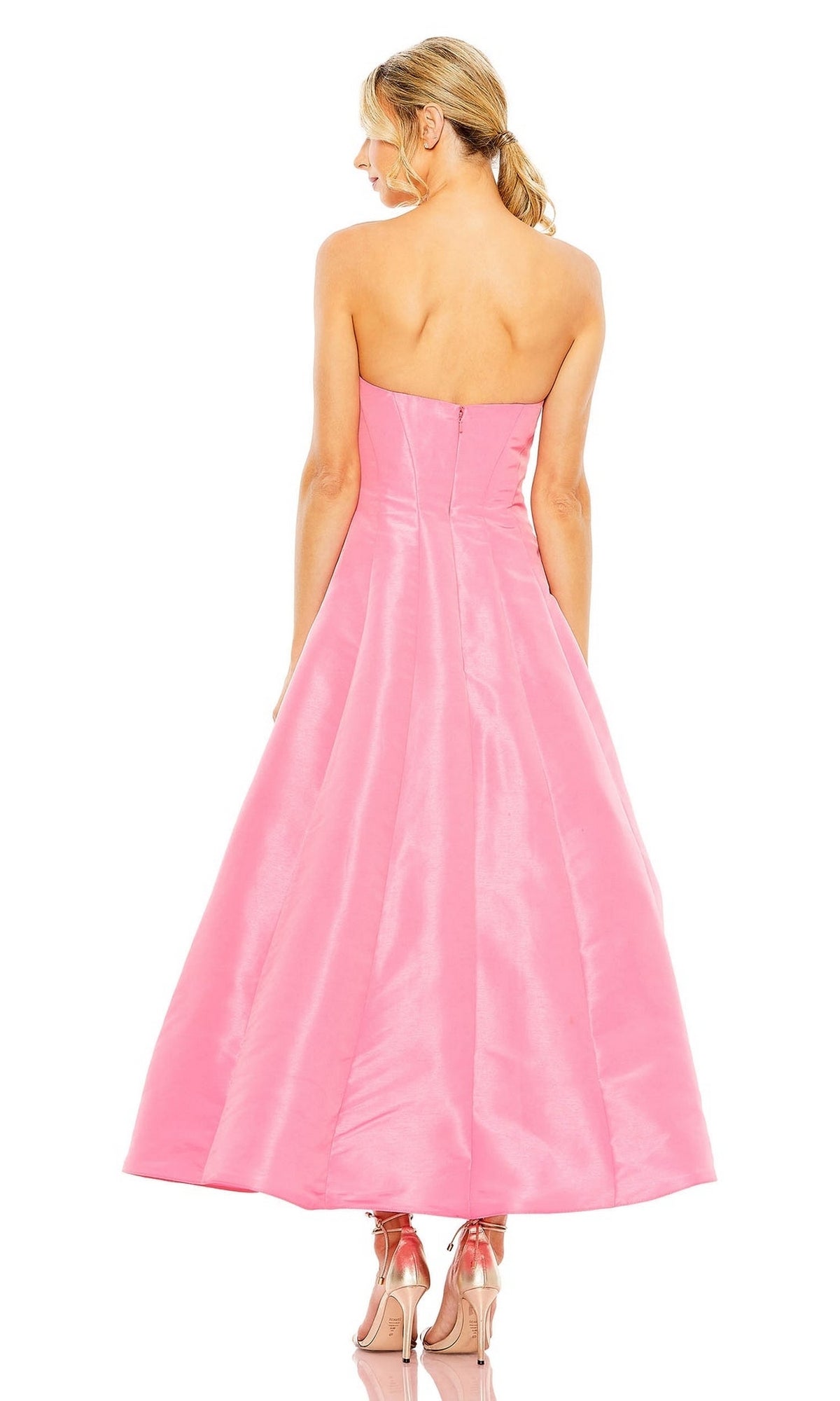 A woman faces away, wearing the Mac Duggal 49605 tea-length wedding-guest dress in pink with a strapless fitted bodice and flared skirt, paired with pink platform heels.