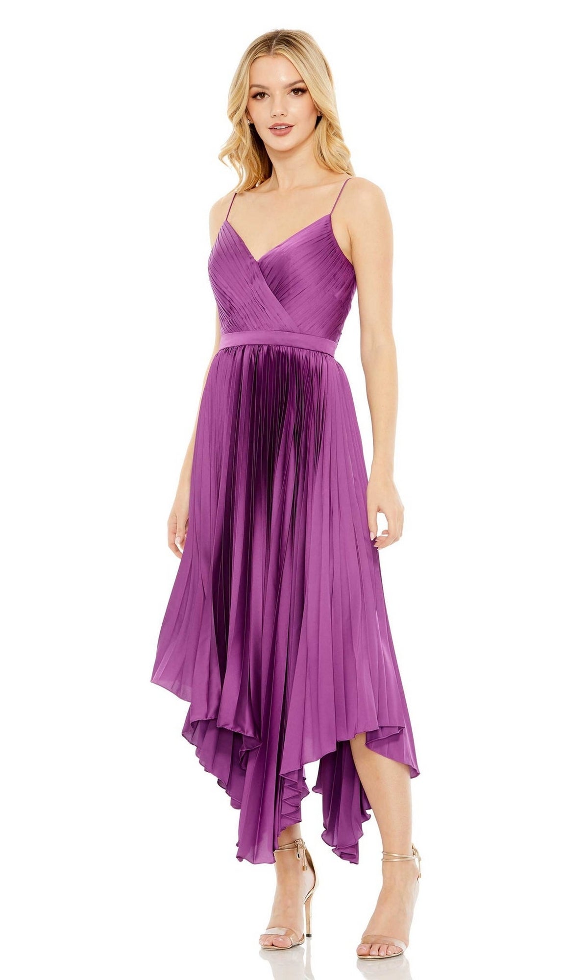 A woman wears the Mac Duggal 49637 short purple wedding guest dress with pleats, a sleeveless design, and an asymmetrical high-low hemline, paired with strappy heels while standing facing forward.