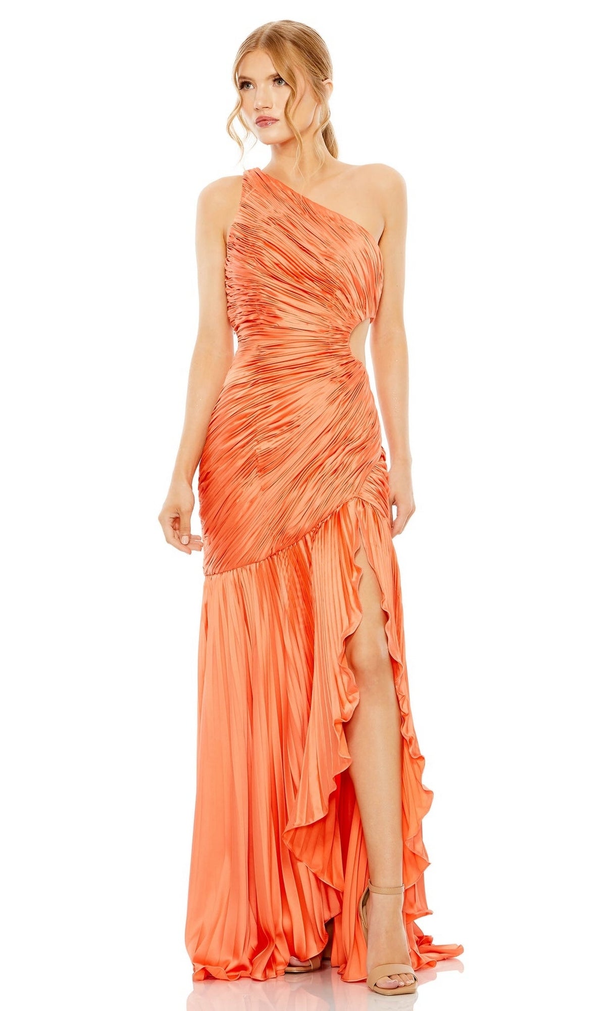 A woman stands in heeled sandals, wearing the Mac Duggal Long Formal Dress 49683—an orange, ruched fitted gown with a one-shoulder design, high slit, and ruffled details.