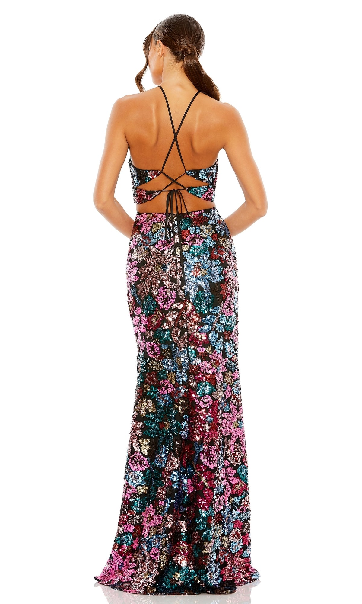 A woman faces away, wearing the Mac Duggal 49695 multicolor sequin formal dress—a floor-length, fitted gown featuring a floral pattern and an open back with crisscrossed straps.