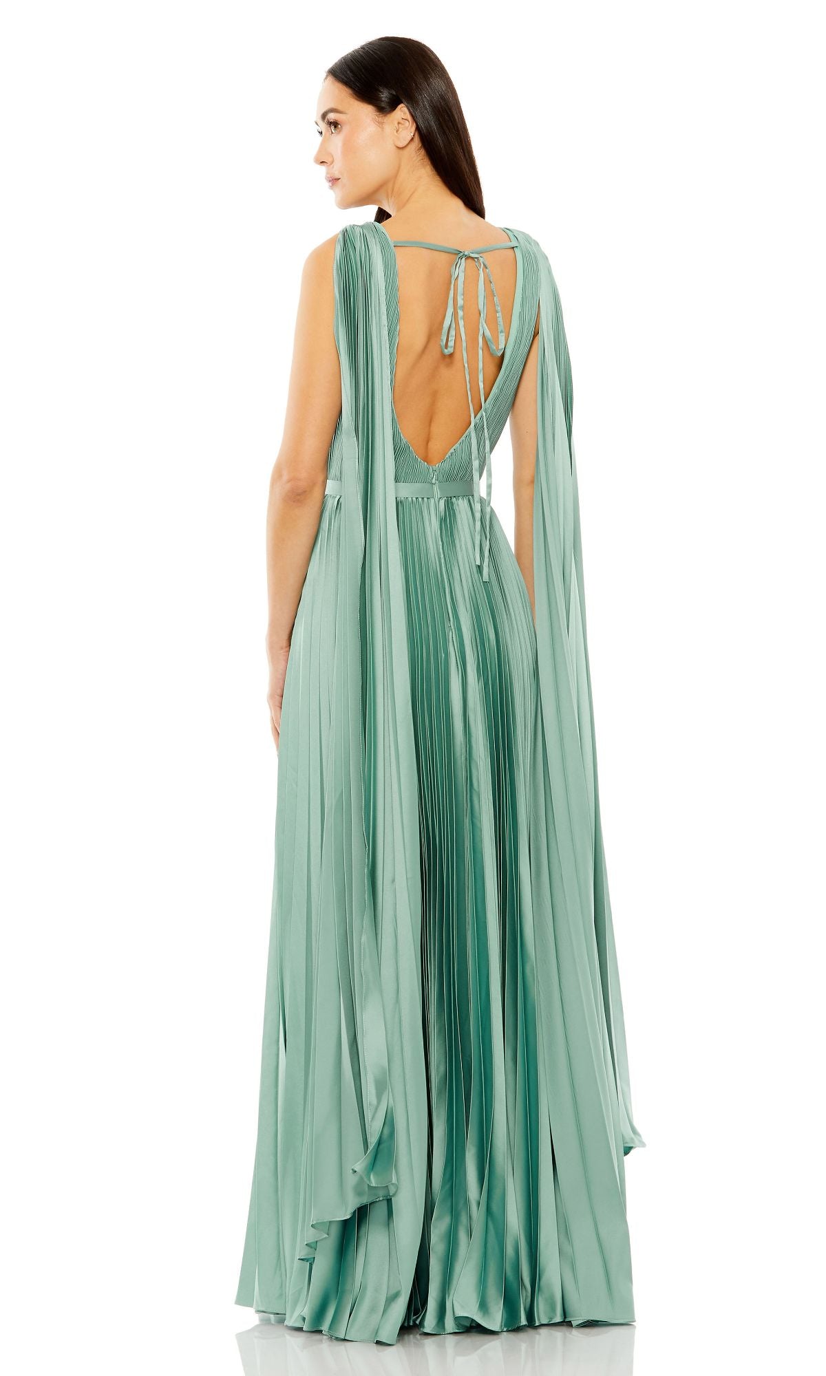 A woman stands facing away in the Mac Duggal 49716 sage green long formal dress, featuring pleated details, a low back, tie accents, and cape-like sleeves.
