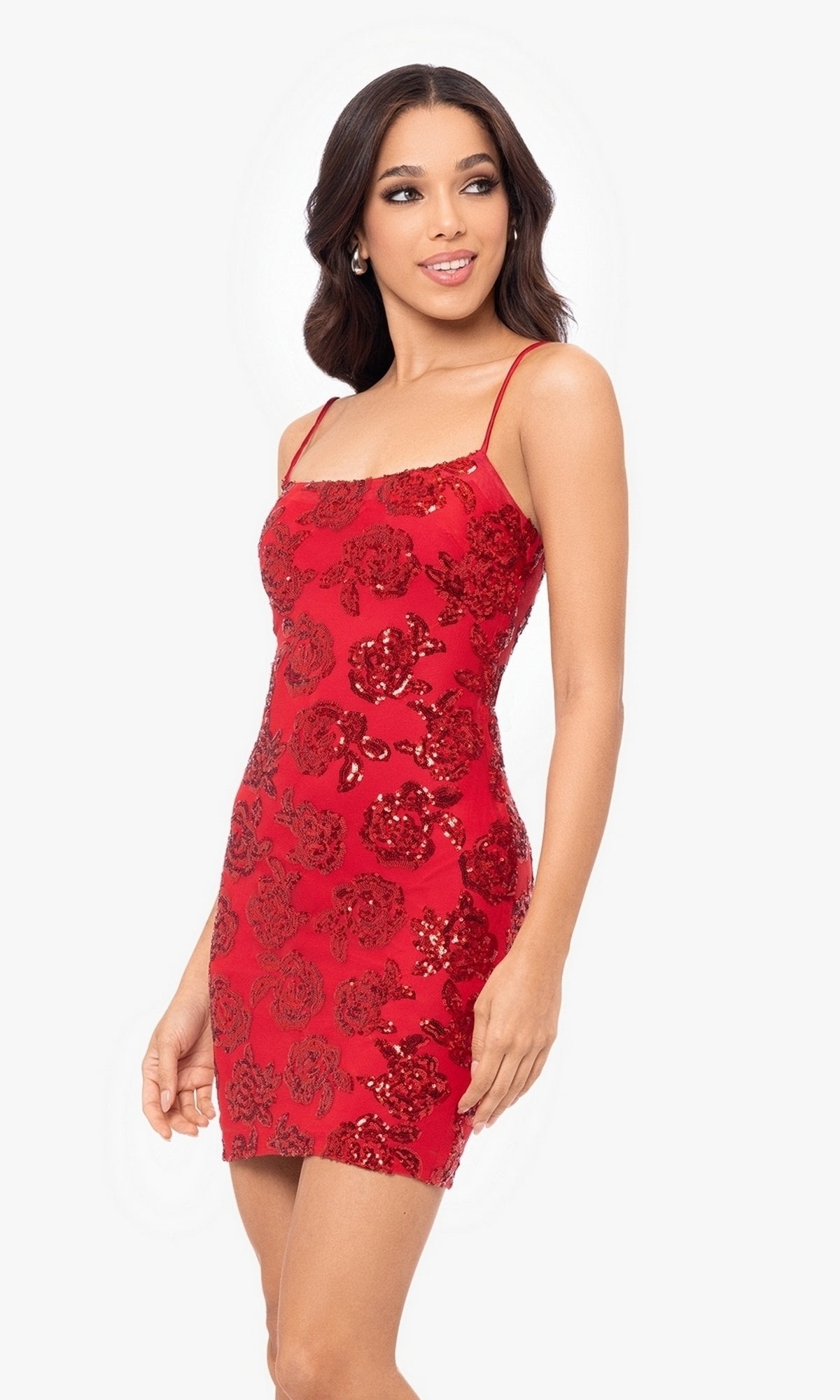 Woman modeling the Cut-Out Short Red Glitter Hoco Dress 4971BN, featuring sparkling sequin floral patterns, against a plain white background.