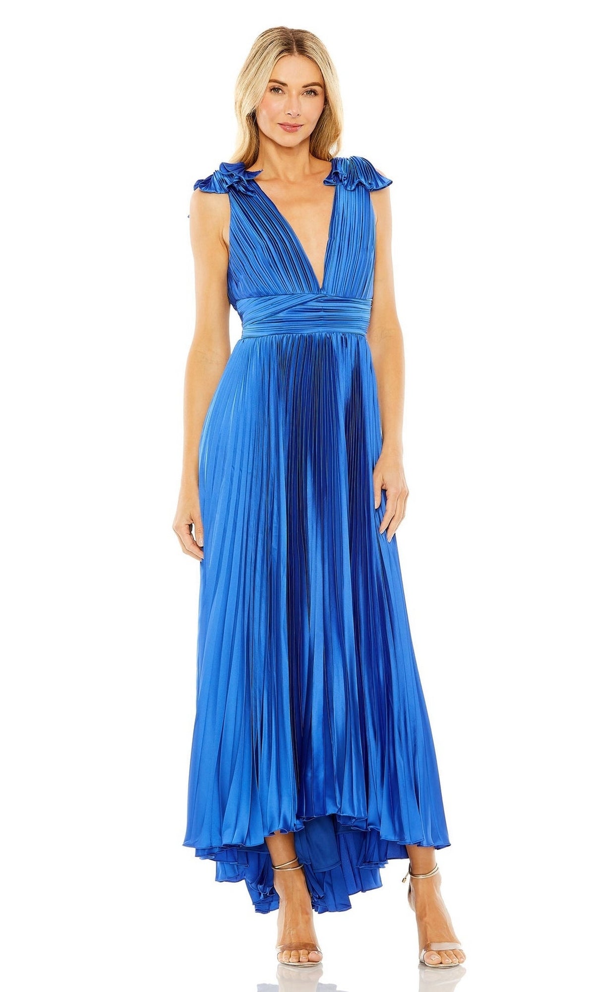 A woman wears the Mac Duggal 49734 Pleated Tea-Length Formal Dress, featuring a sleeveless, deep v-neck design and high-low pleated hem, paired with strappy heels against a plain white background.