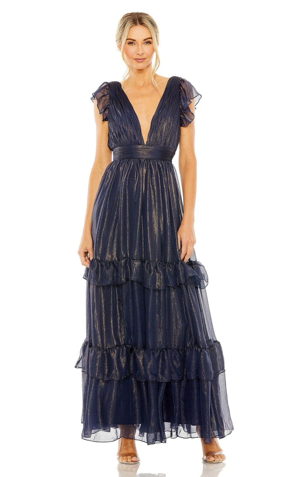 A woman stands facing forward, wearing the Mac Duggal Long Formal Dress 49742—a floor-length midnight blue gown with a shimmery finish, ruffled sleeves, and a tiered skirt.
