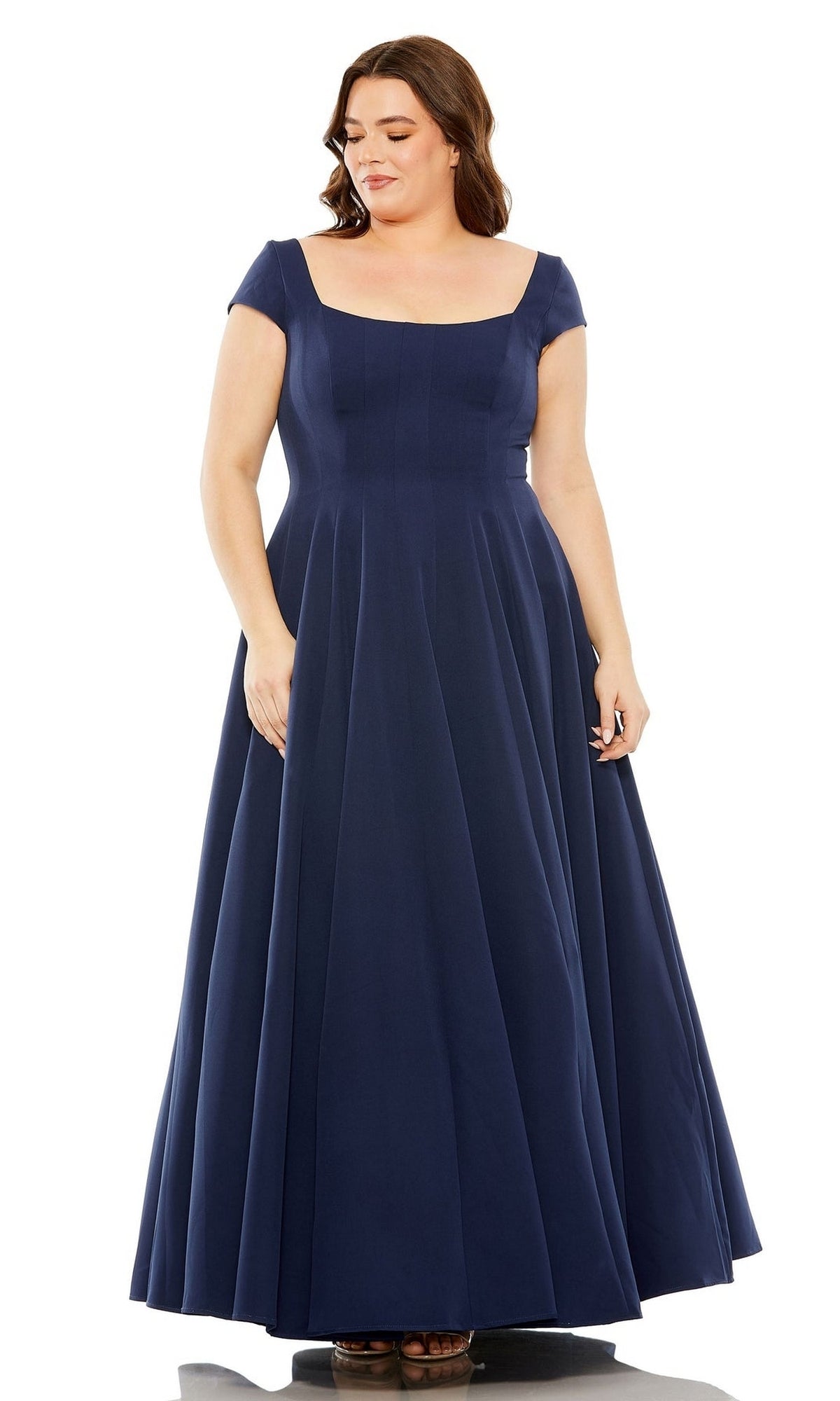 A woman in a Mac Duggal Plus-Size Simple Long Formal Dress 49783W, floor-length, navy blue, with short sleeves and a square neckline, stands against a white background.