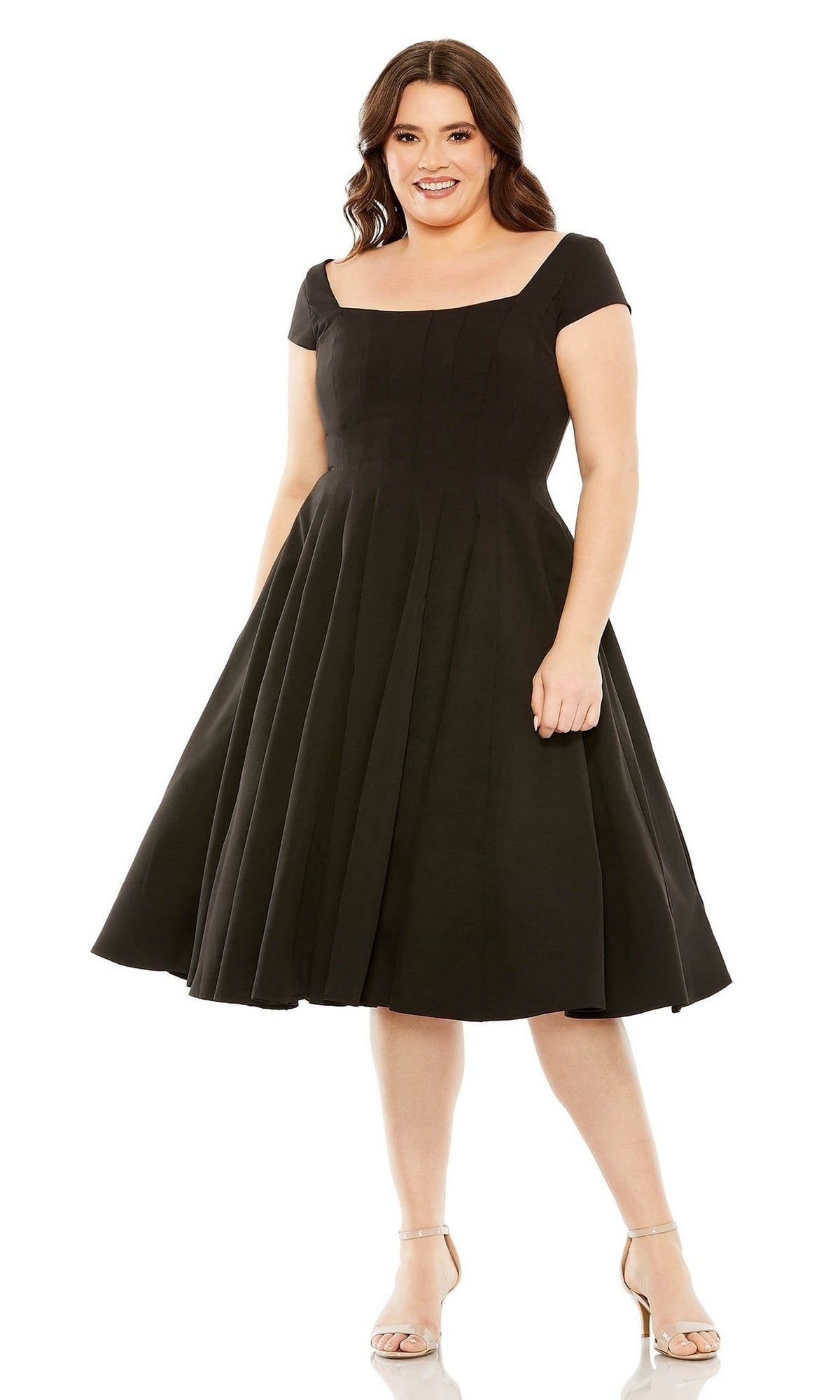 Woman wearing the Plus-Size Short Black Wedding-Guest Dress 49784W featuring short sleeves, a knee-length flared skirt, and square neckline. Smiling in neutral heels, she showcases the perfect A-line party dress for special occasions.