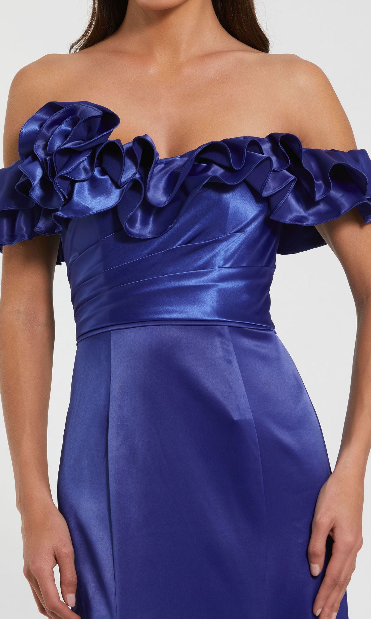 A woman wears the Mac Duggal 49834 Ruffled Long Satin Prom Dress in royal blue, showcasing an off-the-shoulder design with ruffled neckline and a sleek silhouette for a stunning formal or mermaid evening gown style.