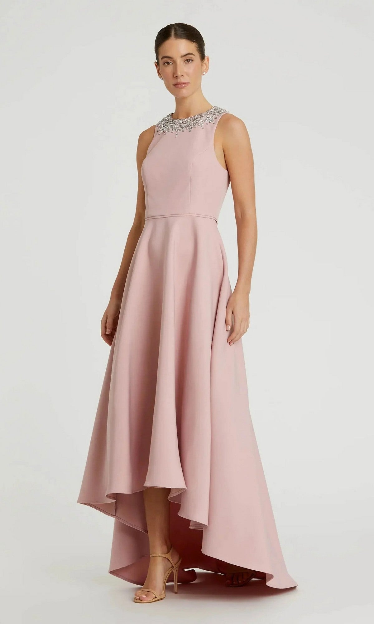 A woman stands in heels against a plain background, wearing the Mac Duggal 49844 High-Low Formal Dress—sleeveless crepe with an embellished neckline.