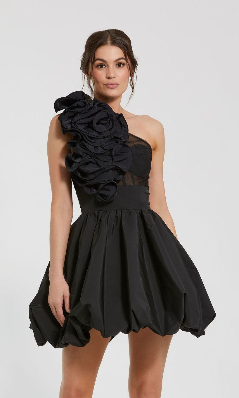 Woman wearing the Mac Duggal 49858 Taffeta Short Black Party Dress, featuring a ruffled one-shoulder design, voluminous bubble hem mini skirt, and floral detail, standing against a plain light background.