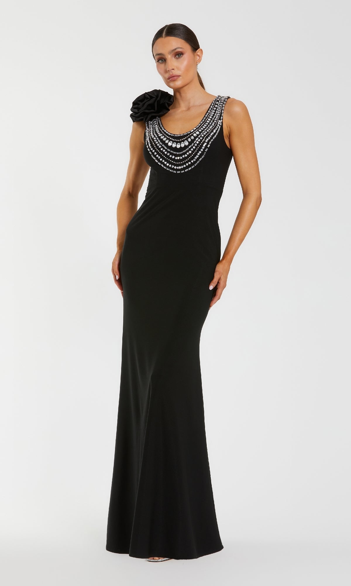 Woman wearing a black evening gown with bead embellishments on a white background