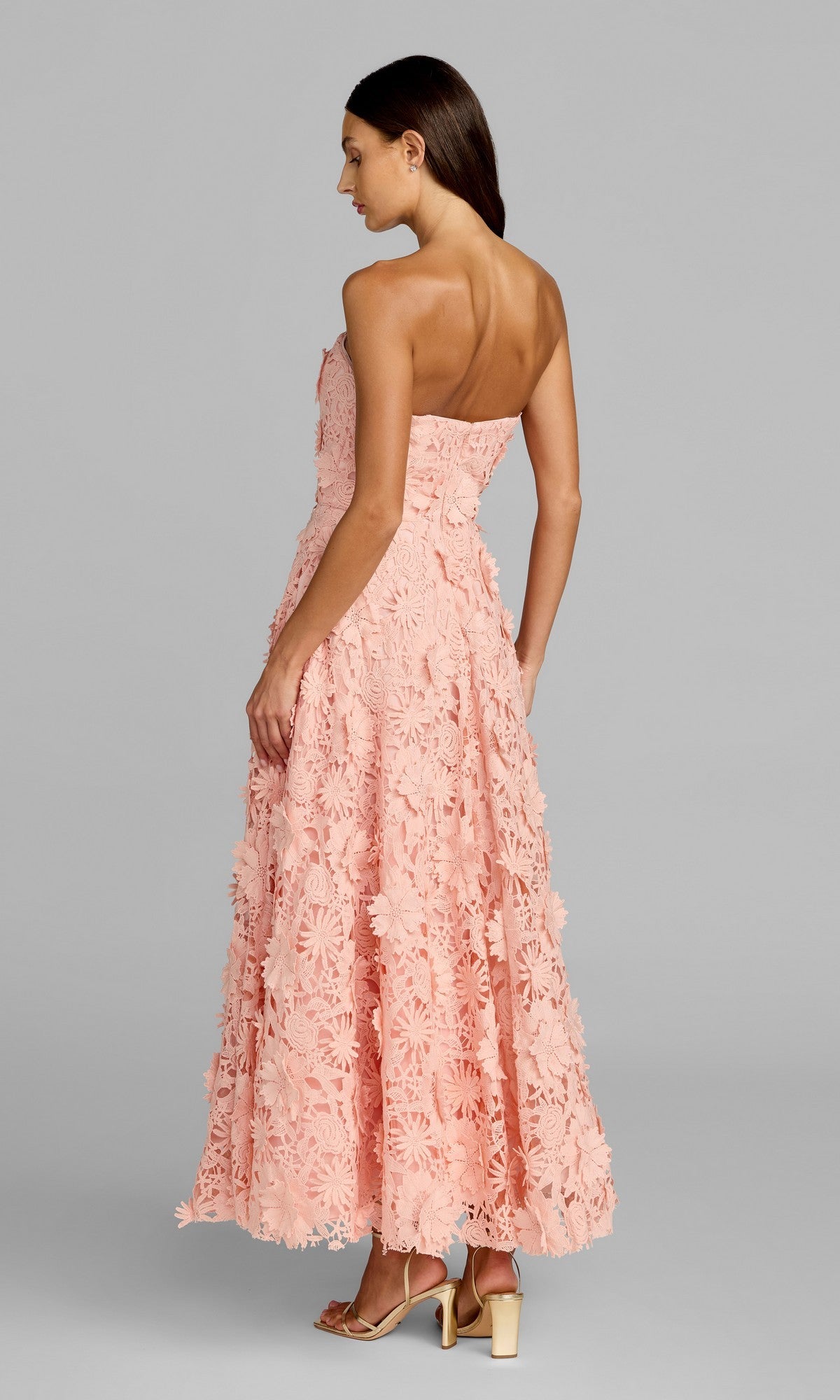 A woman stands facing away on a neutral background, wearing the Mac Duggal 50118 long formal dress—a strapless midi design adorned with elegant floral appliqués.