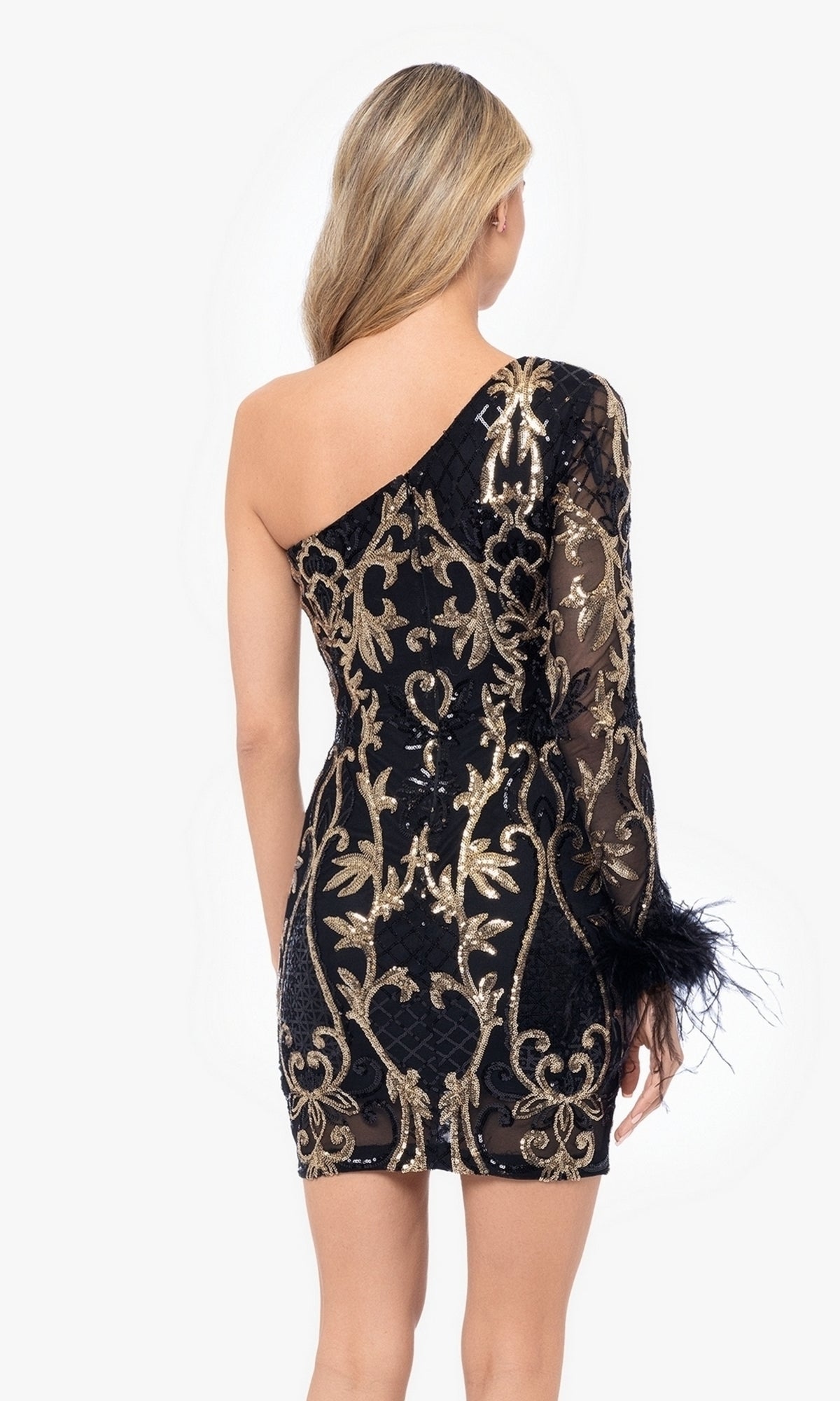 A woman faces away, wearing the One-Sleeve Short Black and Gold Hoco Dress 5013BN—a junior-size homecoming dress with gold sequin embroidery, a sheer long sleeve, and feather details.