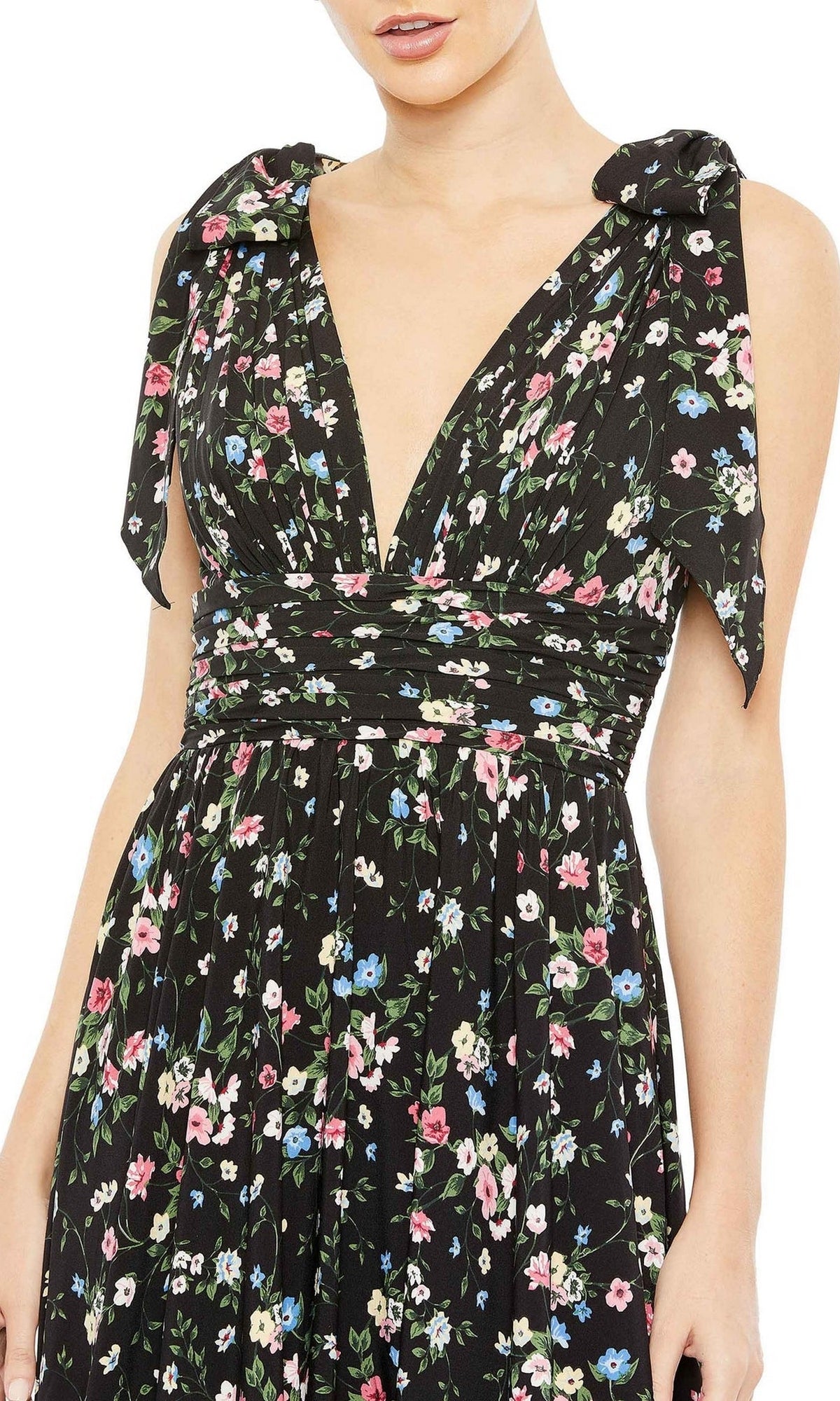 A woman wears the Mac Duggal Long Formal Dress 50657, featuring a sleeveless floral print, deep V-neck, shoulder tie straps, and an elegant A-line silhouette.