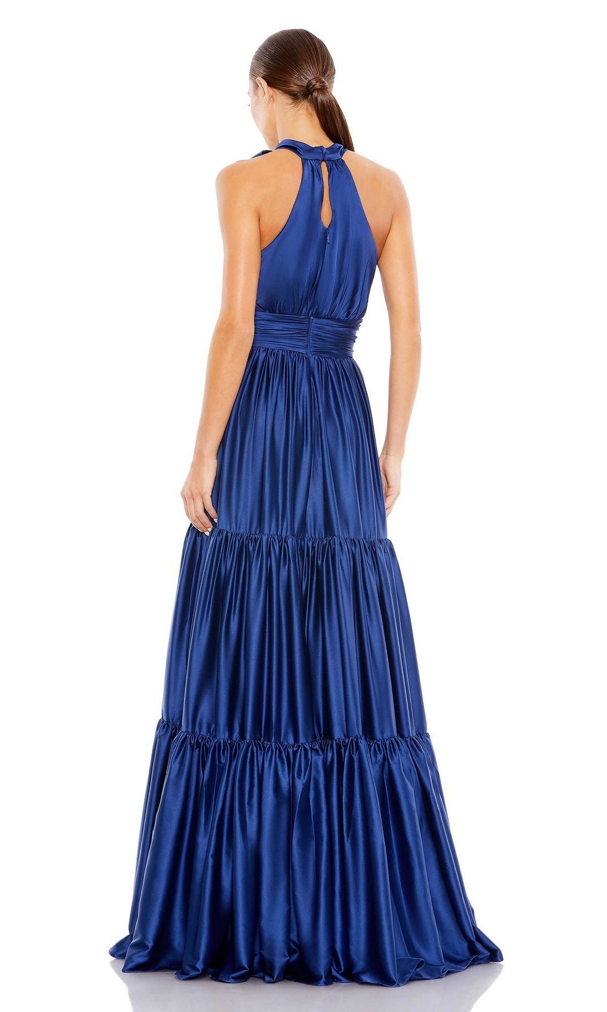 A woman with a low ponytail is elegantly shown from the back wearing the Mac Duggal High-Neck Satin Formal Dress 506581, an A-line, sleeveless satin gown with a bow neckline and tiered ruffled floor-length skirt.