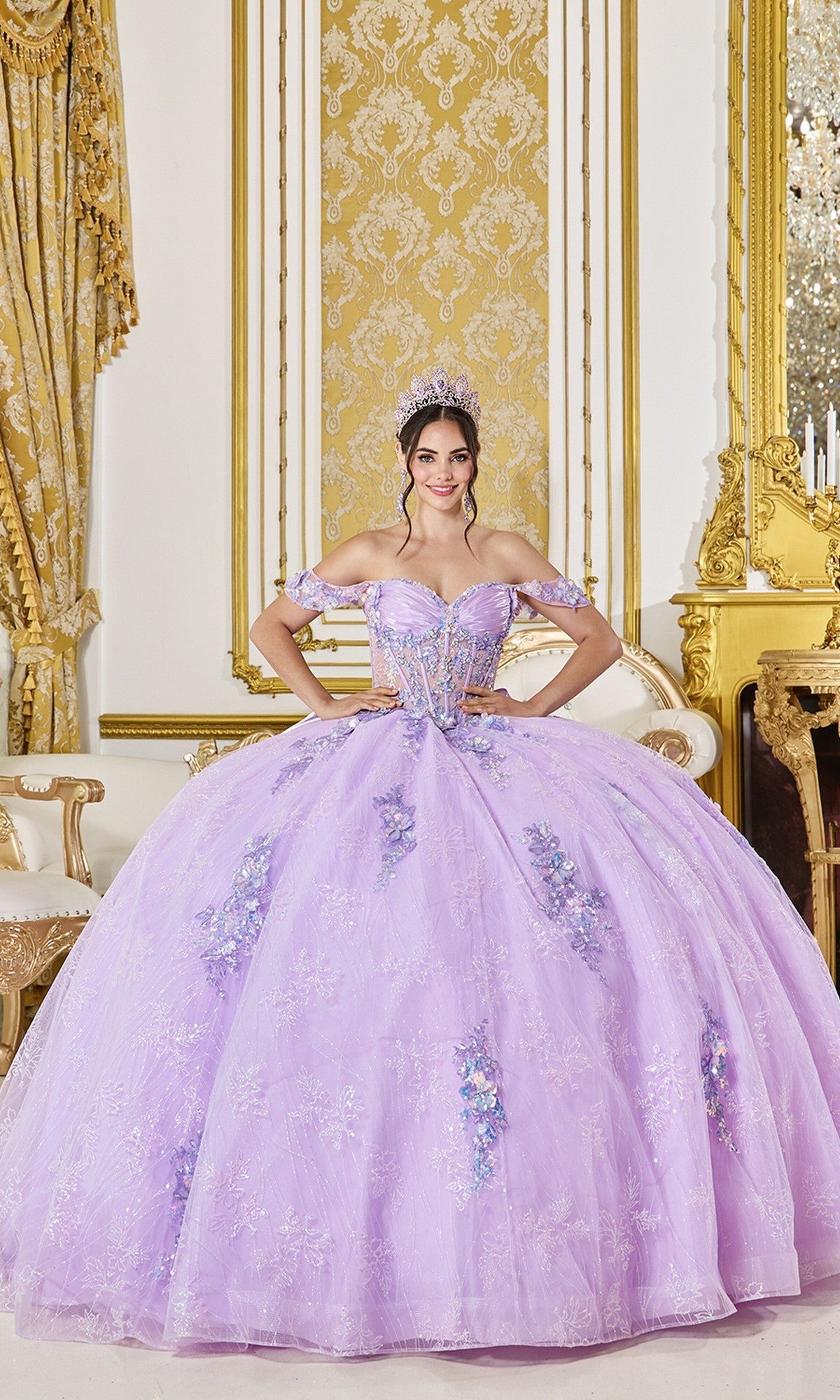 A young woman wears the Quinceanera Dress 5140 By Dancing Queen in lilac, featuring floral embroidery and a tiara, as she stands in an ornate room with gold accents and a large gilded mirror.