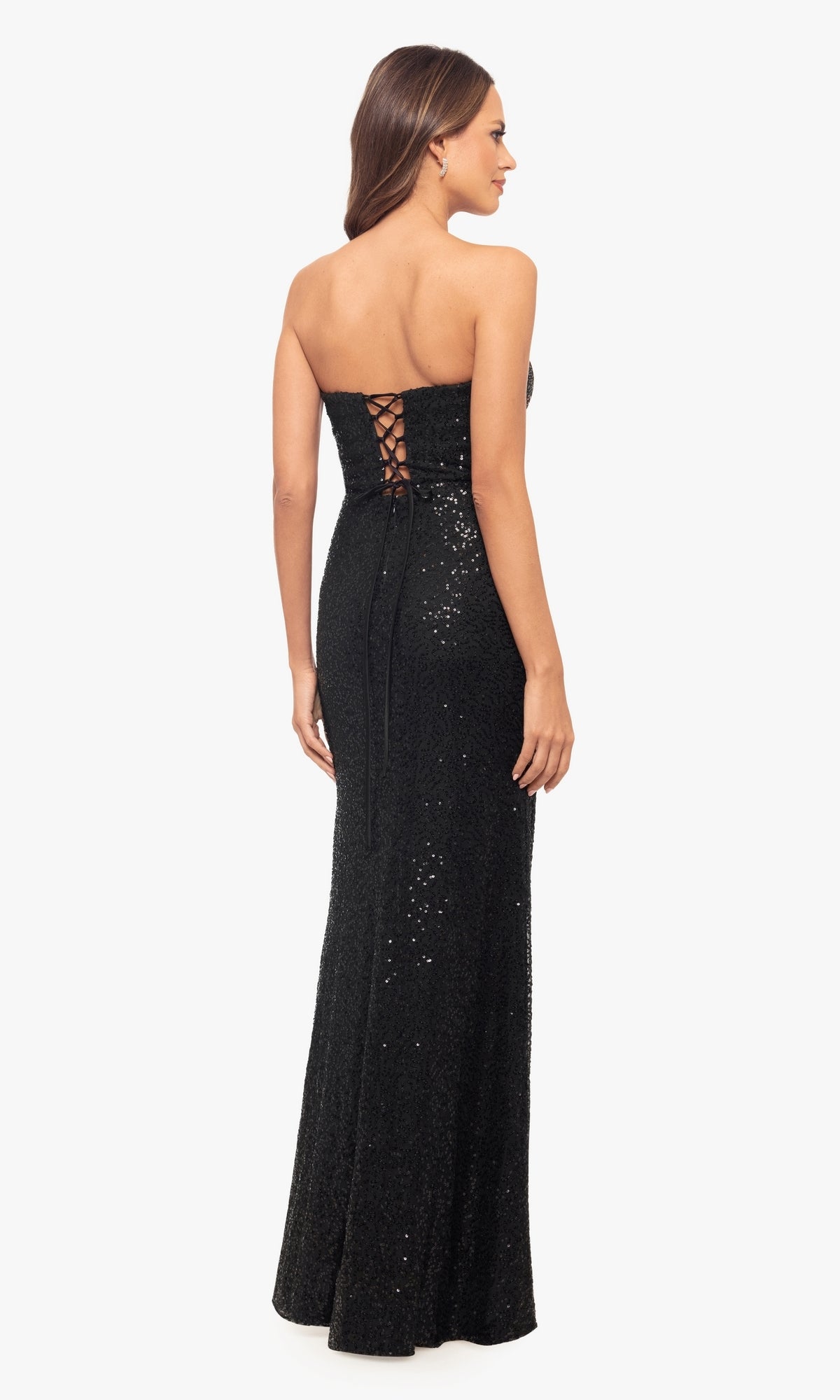 A woman stands slightly to the side wearing the Sequin Long Black Prom Dress: Blondie Nites 5181BN, a strapless, floor-length gown with sparkling sequins and a lace-up back for an elegant prom look.