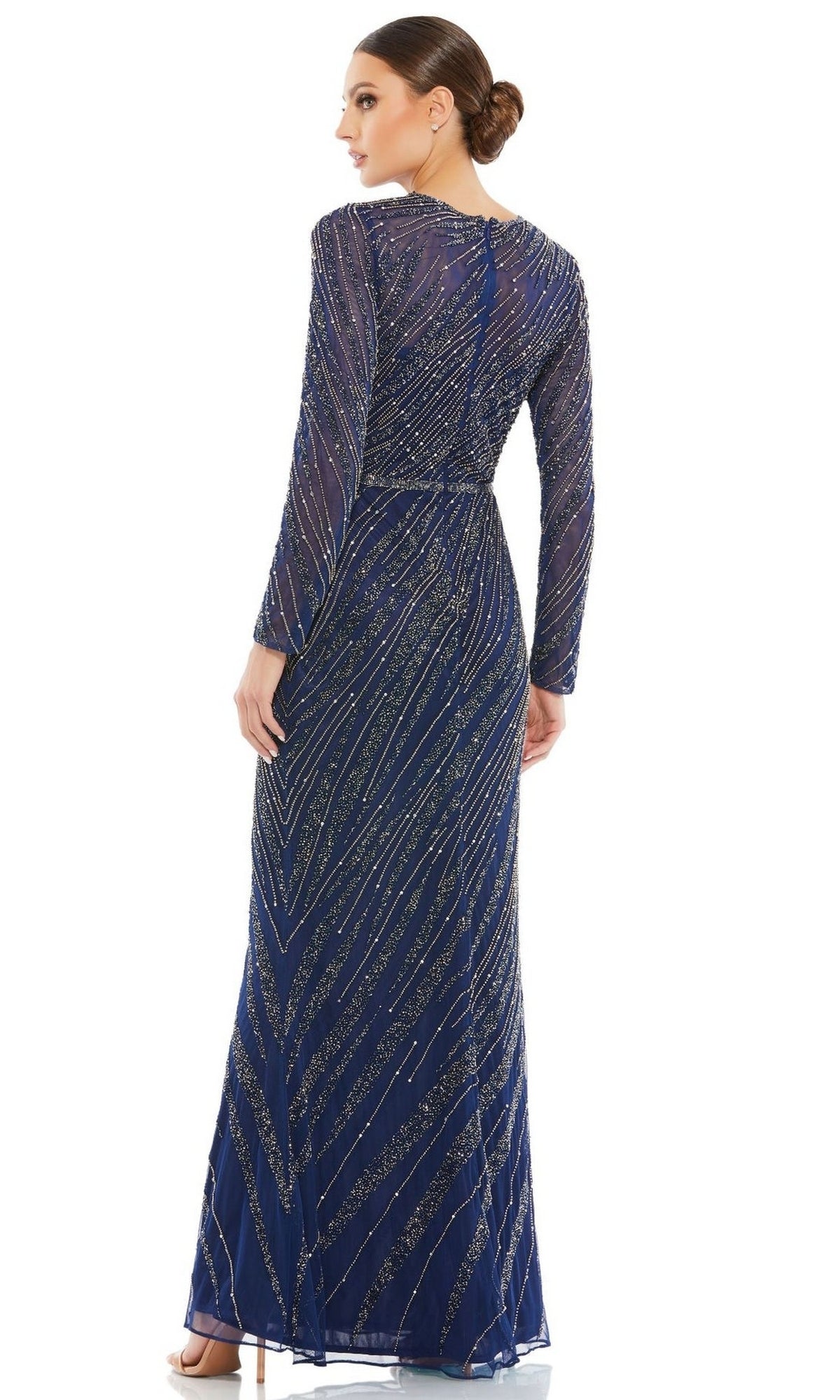 A woman stands with her back turned, wearing the Mac Duggal 5240: a navy blue long sleeve formal dress with a high neckline, floor-length silhouette, and shimmering diagonal sequin embellishments.