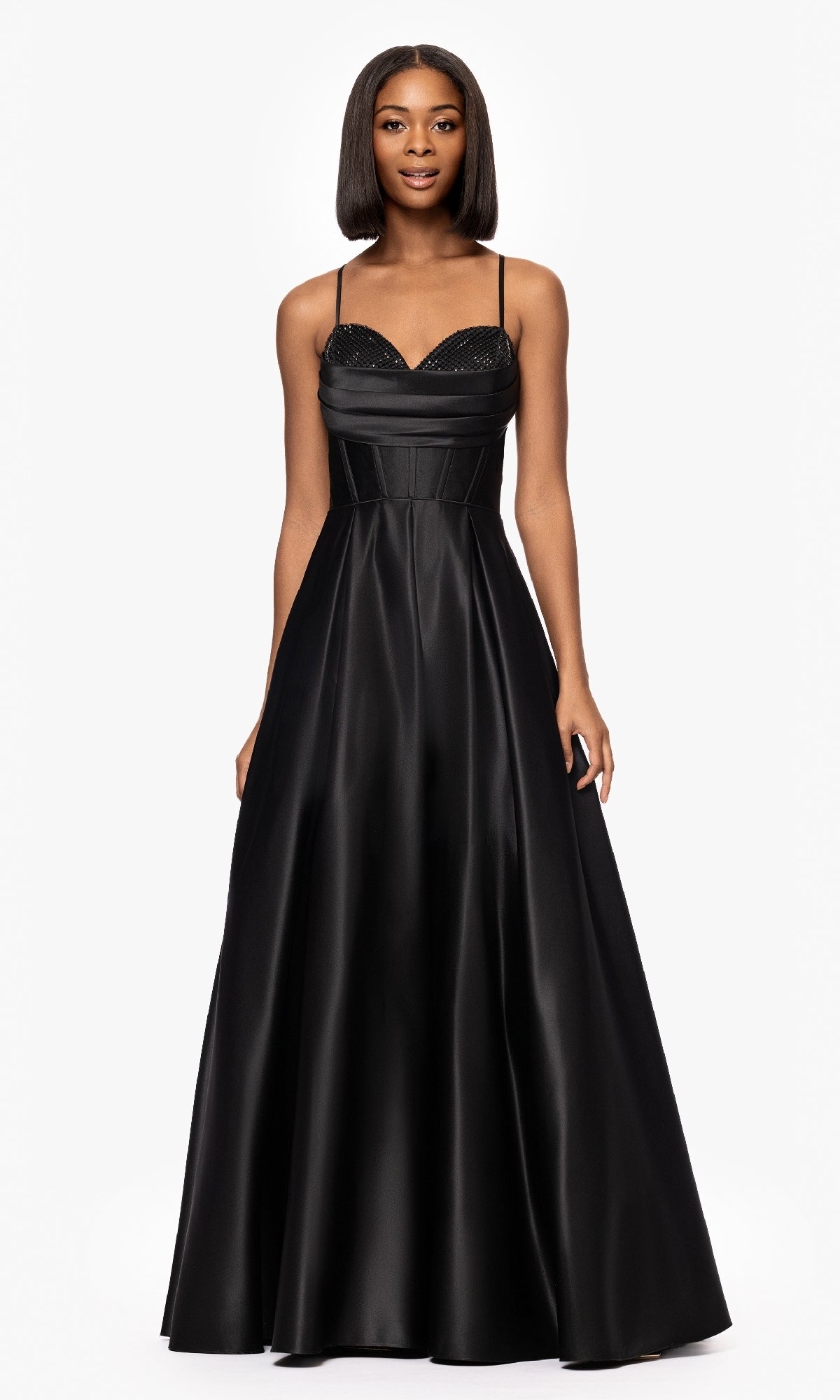 A woman stands against a plain white background wearing the Long Black A-Line Prom Dress: Blondie Nites 5333BN, featuring spaghetti straps and a fitted bodice.