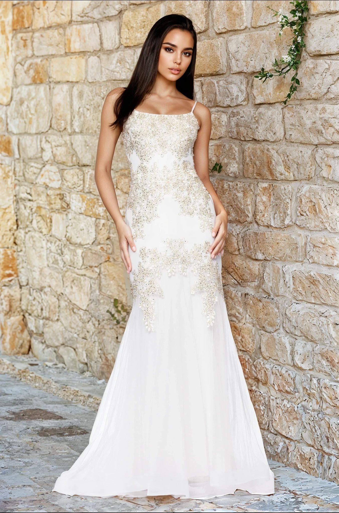 A woman models the Blondie Nites 5455BN long prom dress with gold lace appliques, standing in front of a stone wall and looking at the camera with her hands by her sides.