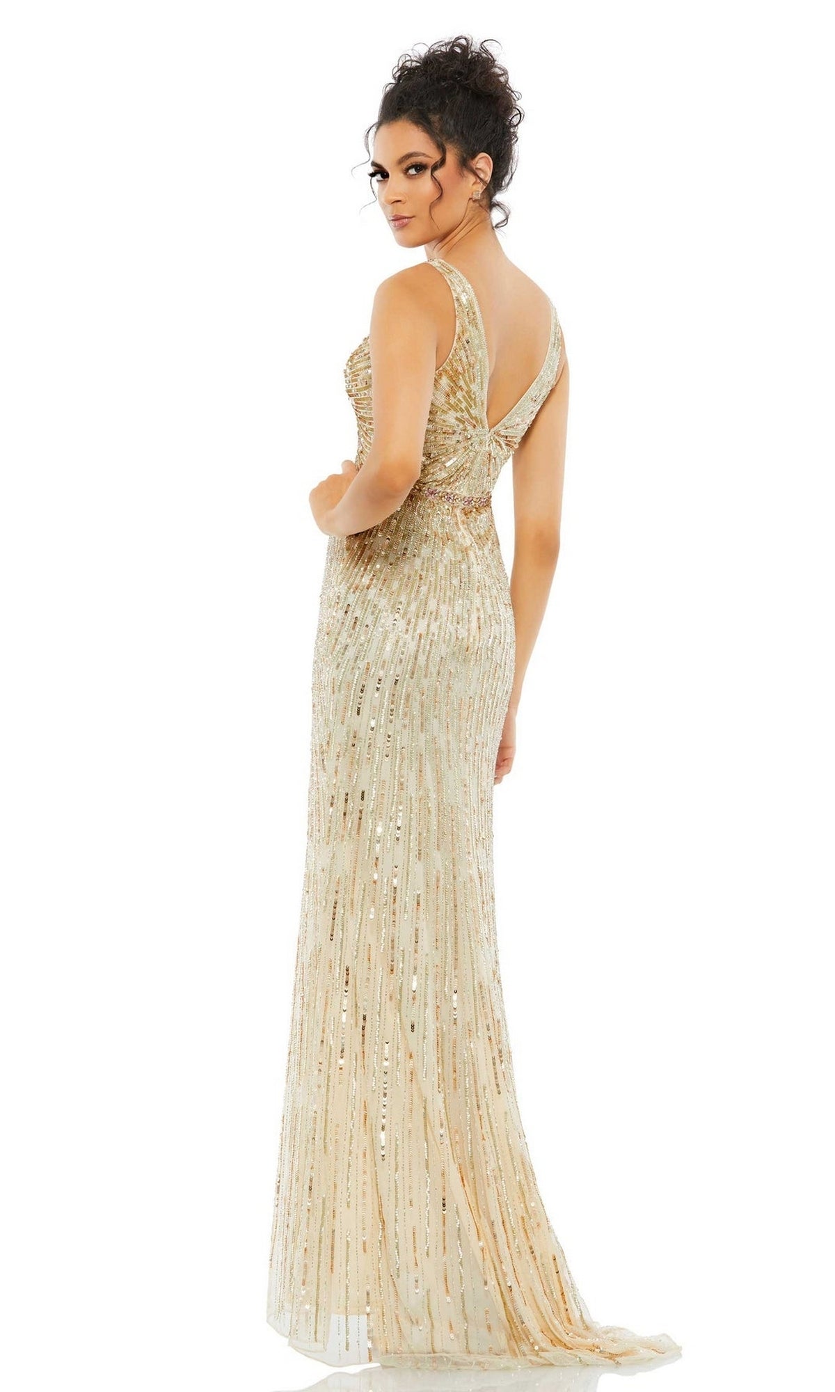 A woman models the Long Formal Dress 5483 by Mac Duggal—a floor-length, gold sequin beaded gown featuring a fitted bodice and one-shoulder strap—as she stands looking over her shoulder.