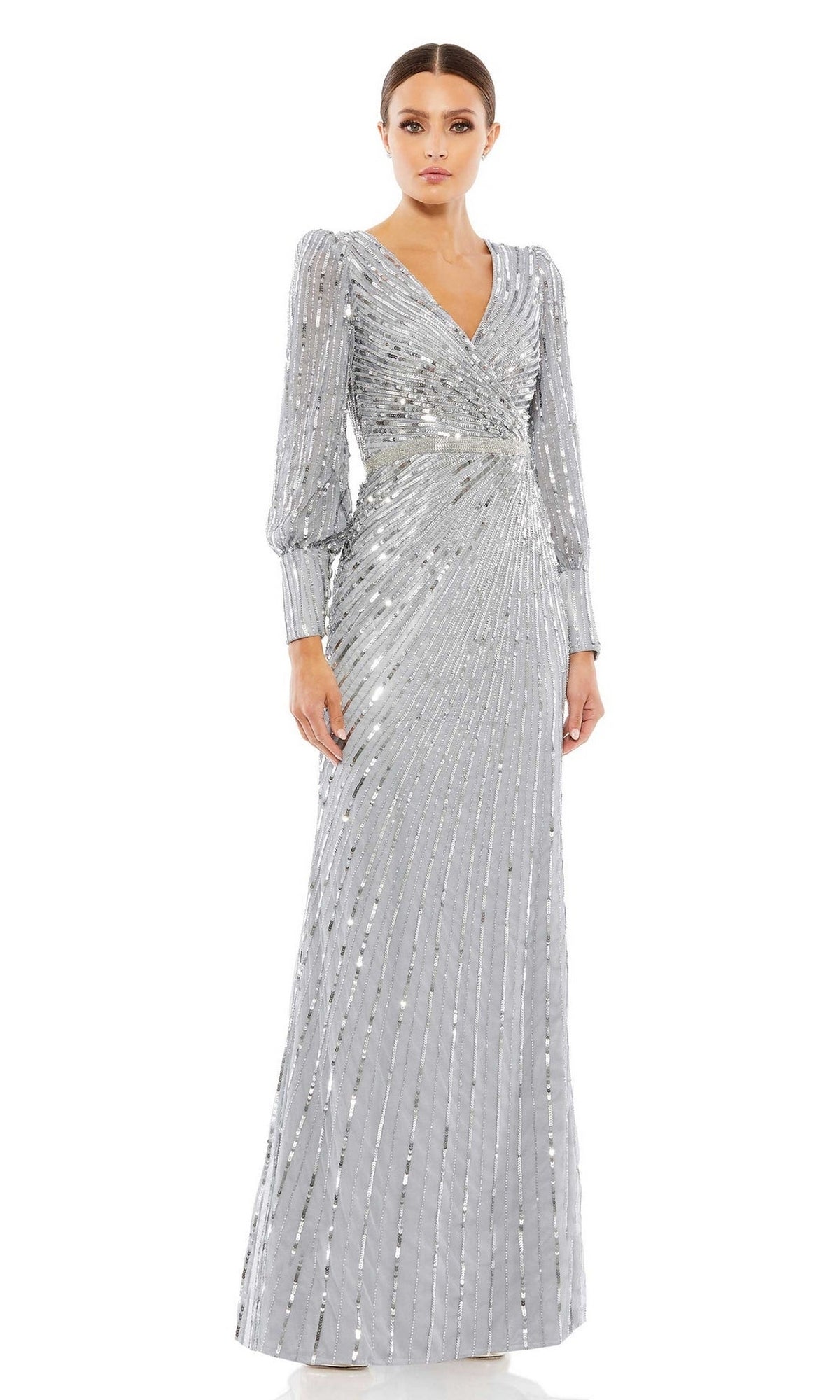 Woman models the Mac Duggal 5501, a long-sleeved silver sequin formal dress with a V-neckline and pleated detailing—an elegant, floor-length choice for mother of the bride—against a plain white background.