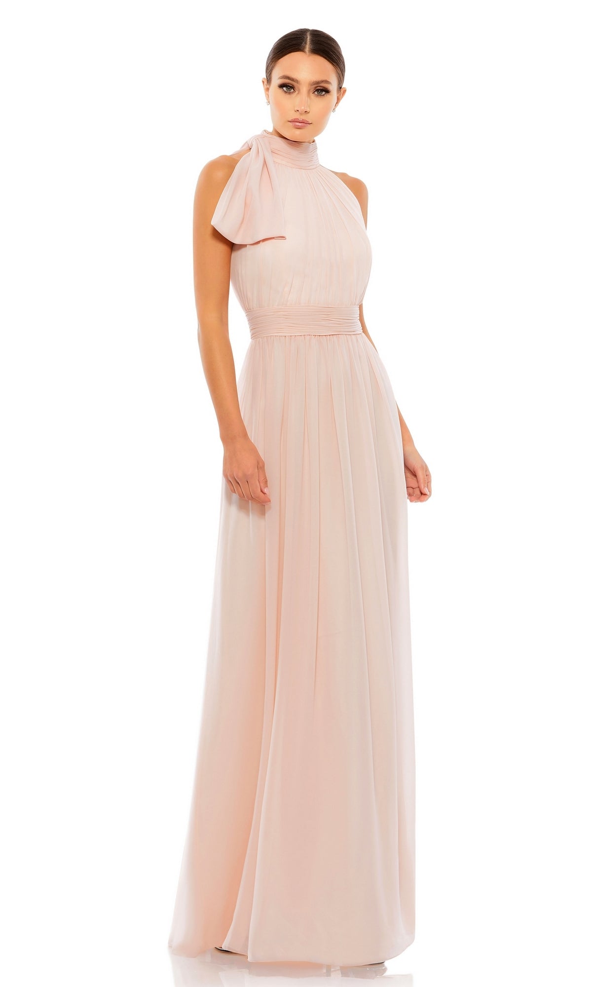 A woman wears the Mac Duggal 55035 High-Neck Long Formal Dress, a floor-length pale pink gown with a high neck and bow detail on one shoulder, set against a white background.