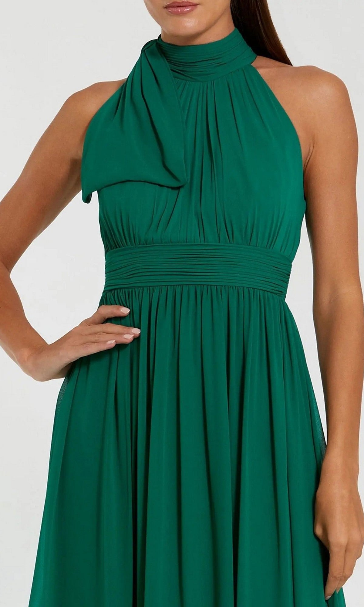 Wearing the Mac Duggal 55035 High-Neck Long Formal Dress in green, featuring a sleeveless design with a gathered neckline and waistband, a person poses with one hand on their hip.