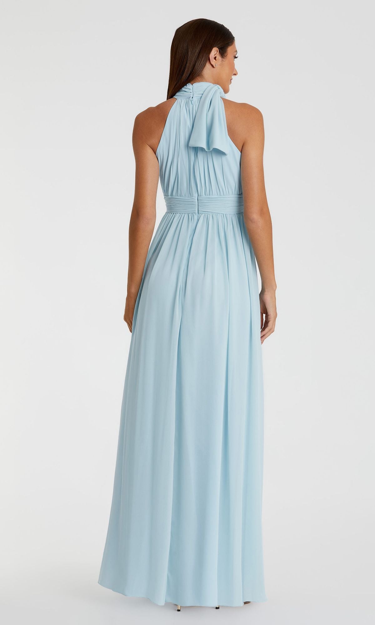 A woman faces away, wearing the Mac Duggal 55035 High-Neck Long Formal Dress in light blue, featuring pleated detailing and a draped back bow.