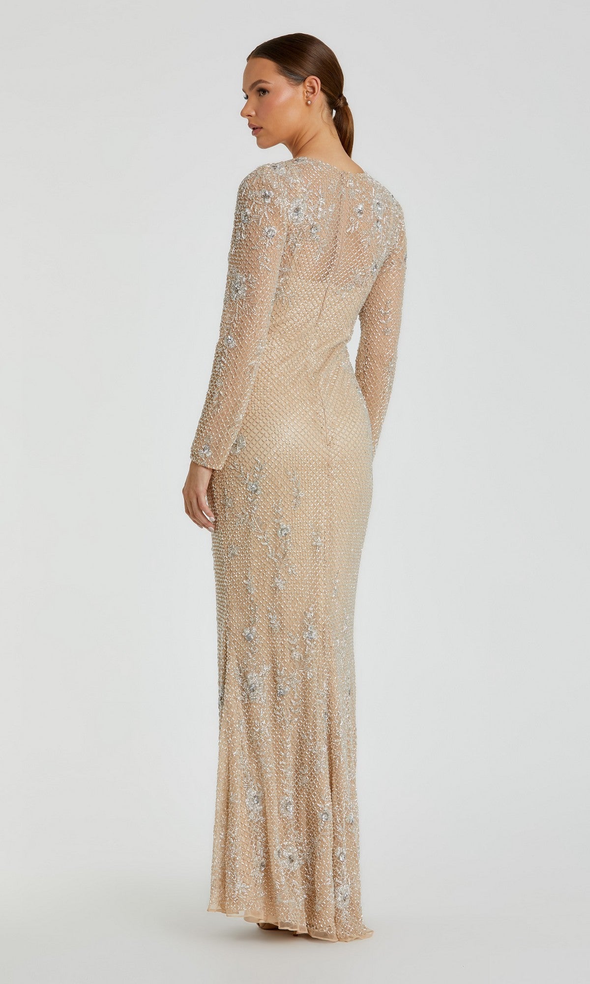Woman standing in a floor-length, long-sleeved Mac Duggal 5504 gold beaded formal gown, facing away with her head turned to the side against a plain light background.