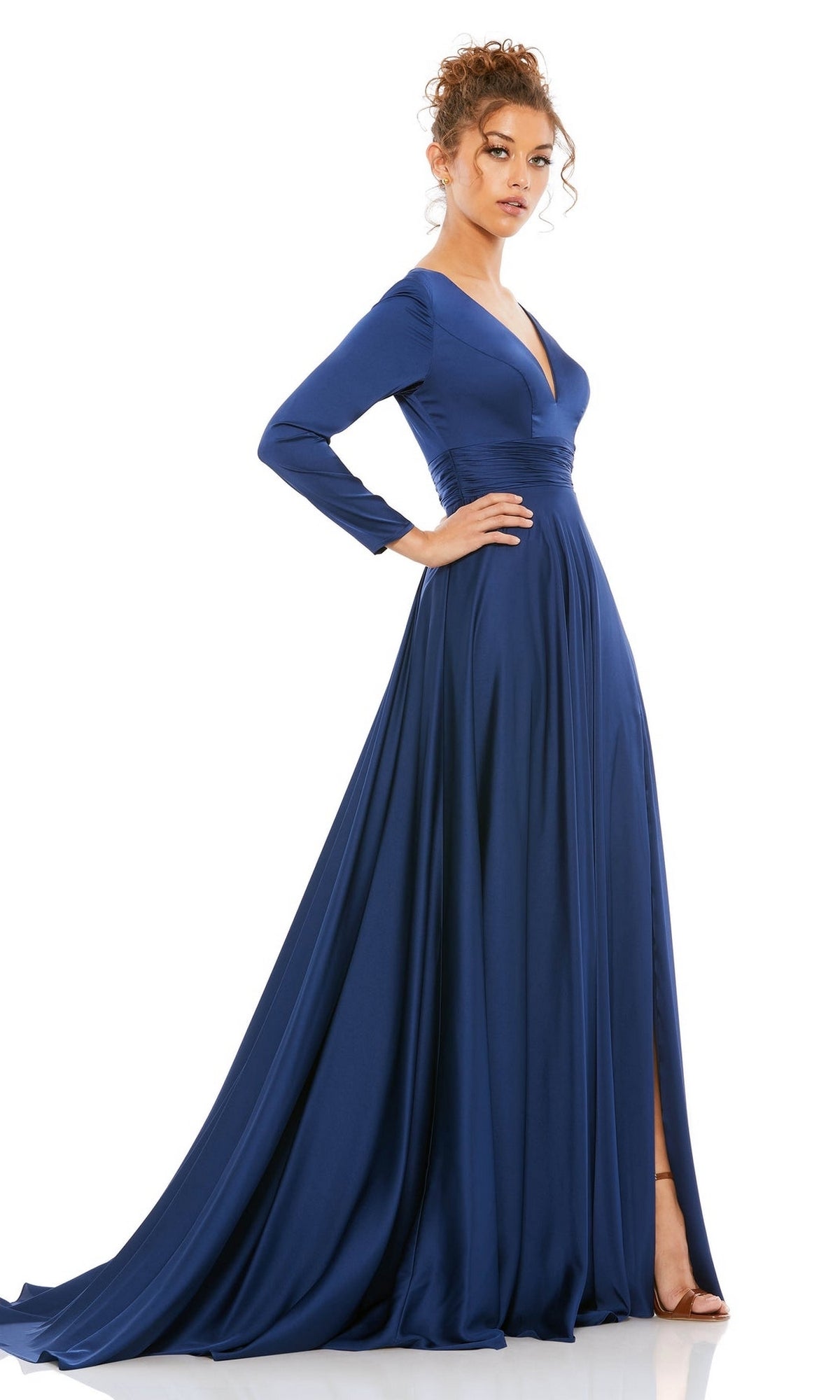 A woman wears the Mac Duggal 55245 Long Sleeve Long Formal Dress, featuring a deep blue A-line silhouette, V-neckline, and a high-slit evening gown skirt.