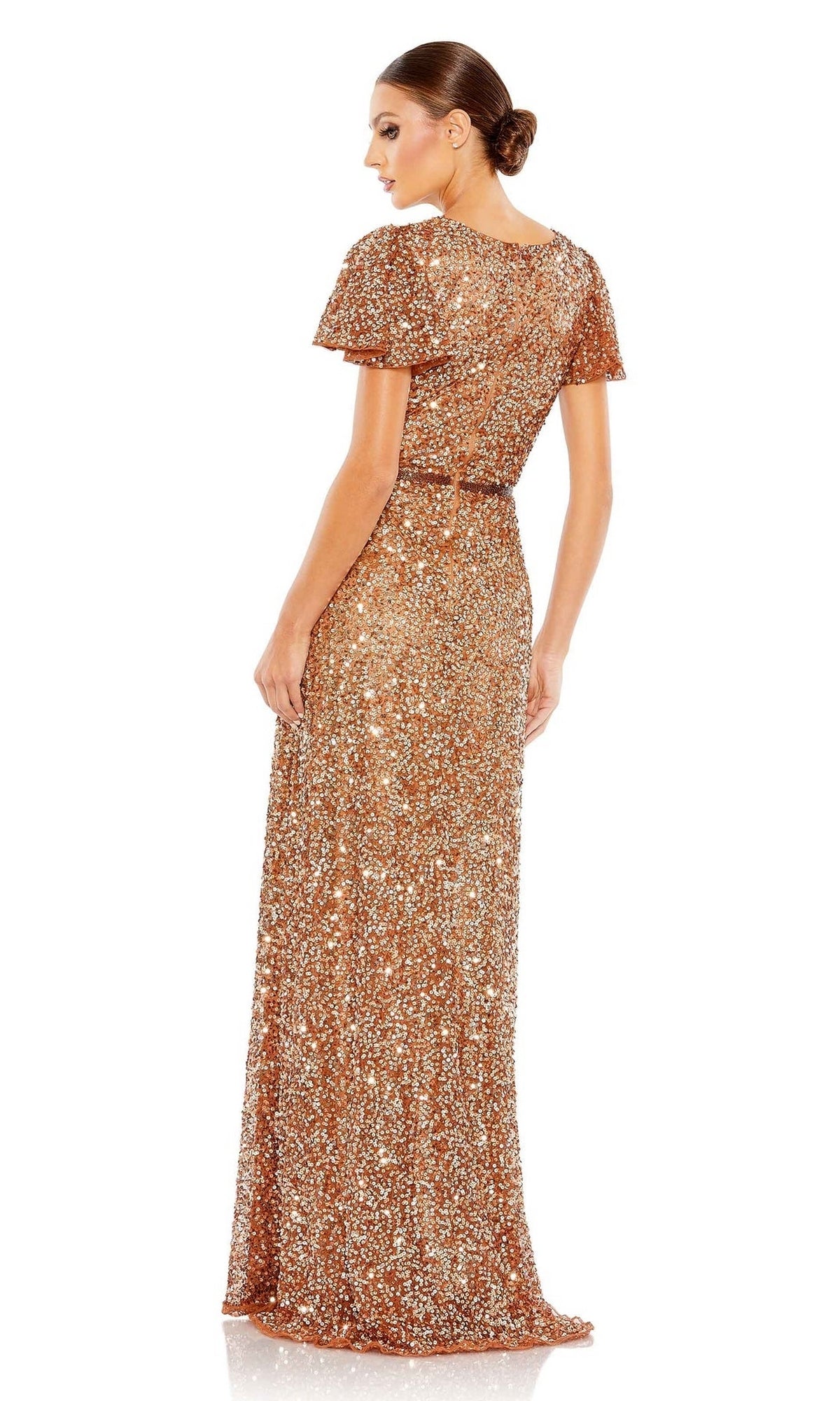 A woman with a low bun faces away, wearing the Mac Duggal 5540—a floor-length, short-sleeve formal dress in rose gold sequins with a fitted waist.