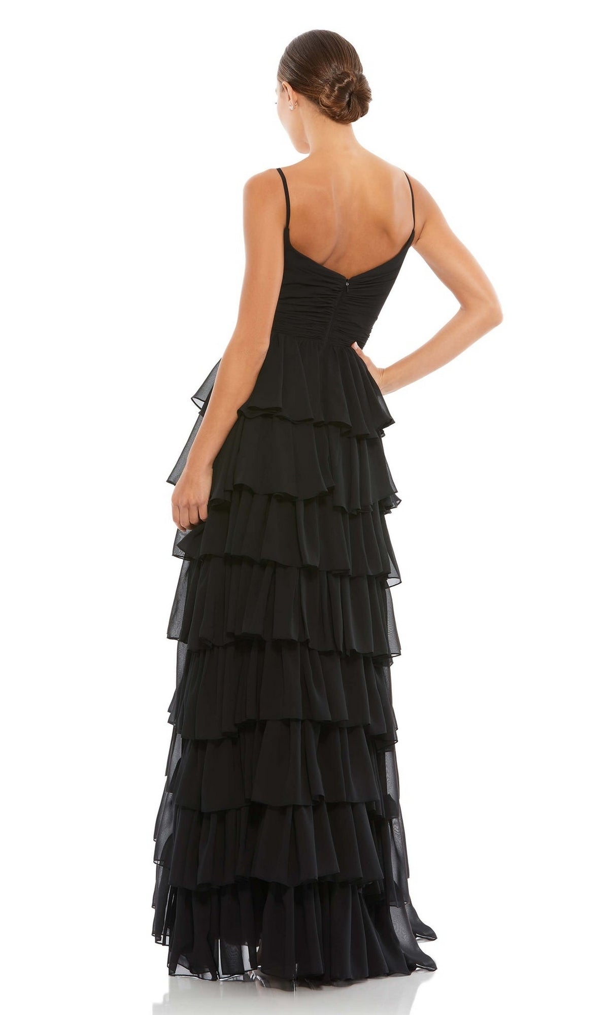 A woman stands with her back to the camera, hair in a neat bun, wearing the Mac Duggal 55416 Ruffled Long A-Line Prom Dress—sleeveless and elegant in black.