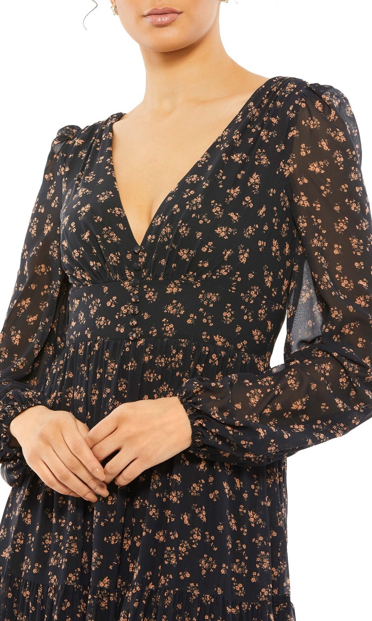 A woman stands with her hands folded, wearing the Long Formal Dress 55431 by Mac Duggal—a black gown featuring long sleeves, a small floral print, and a deep V-neckline.