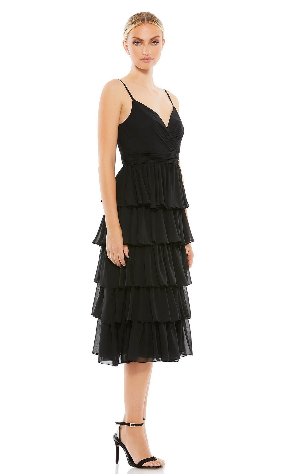 A woman models the Mac Duggal 55437 Black Midi Wedding Guest Dress—sleeveless, with tiered ruffles and spaghetti straps—paired with black heels against a white background, making it a chic black wedding guest dress choice.