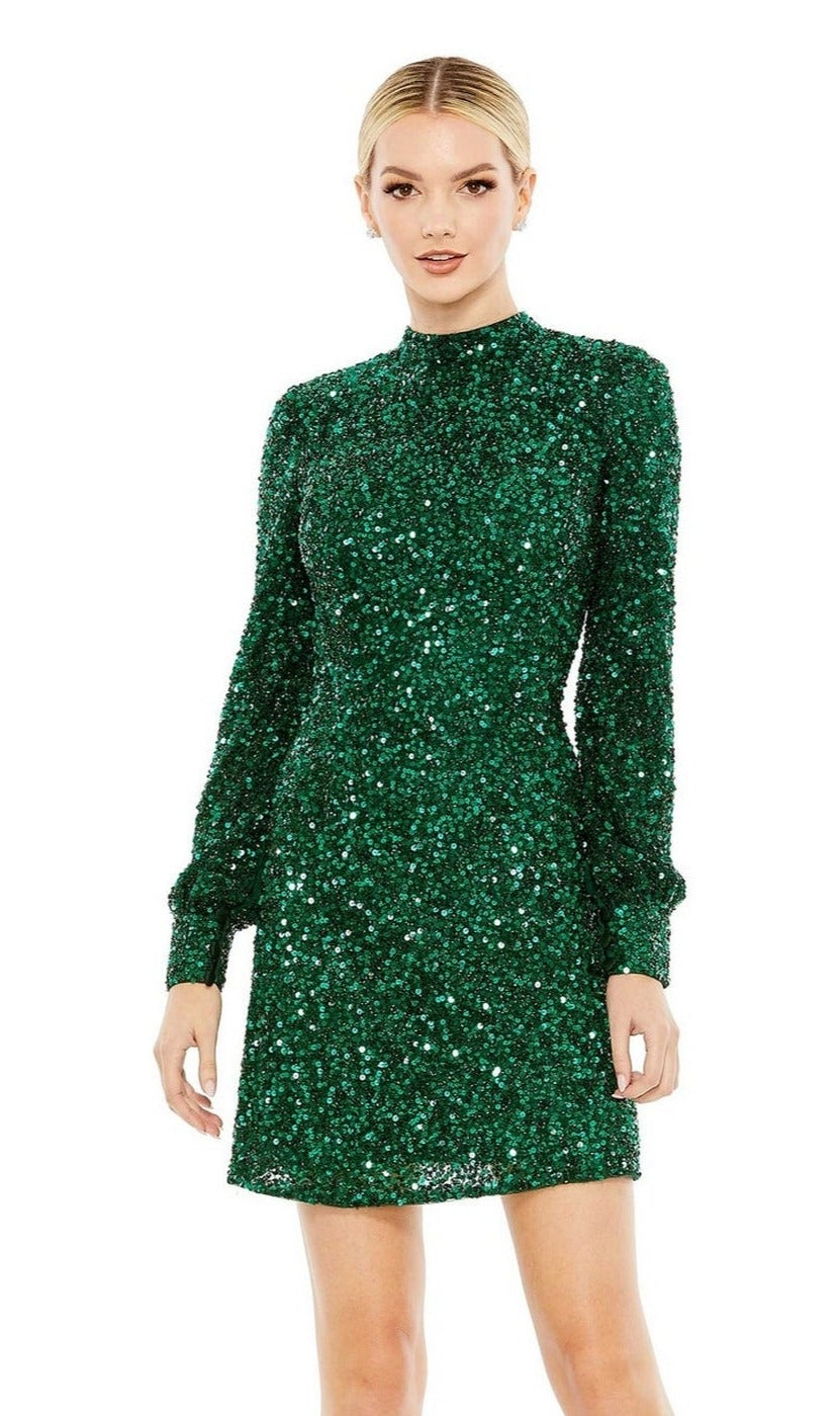A woman wears the Mac Duggal Short Homecoming Dress 5545—an emerald green, fitted, long-sleeve sequin mini dress with a high neckline—posing against a plain white background. Perfect for a glamorous homecoming look.