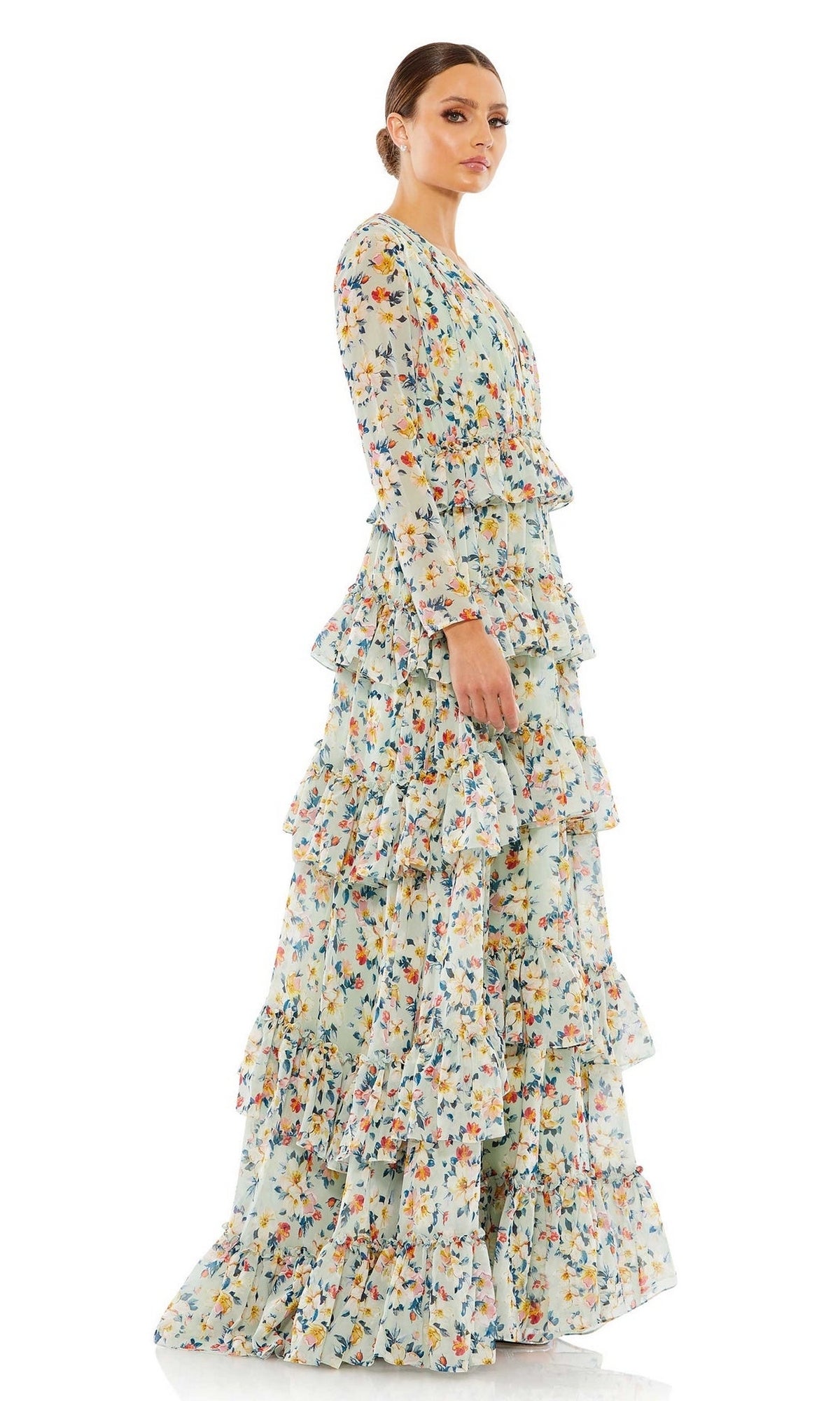 A woman stands sideways against a white background, showcasing the elegant silhouette of the Mac Duggal Long Formal Dress 55664, which features a floor-length design with floral patterns and ruffled tiers.