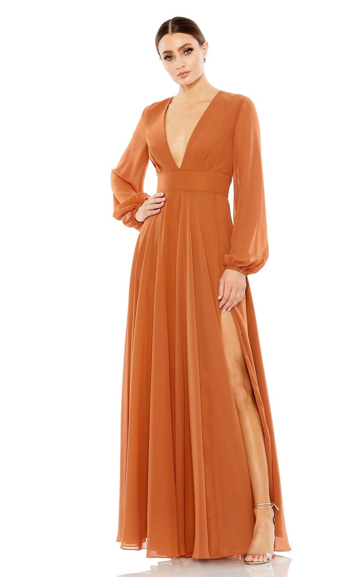 A woman poses in the Mac Duggal 55682, a rust-orange long sleeve chiffon formal dress with a deep V-neck and thigh-high slit, styled with strappy heels—an elegant choice perfect for a mother of the bride.