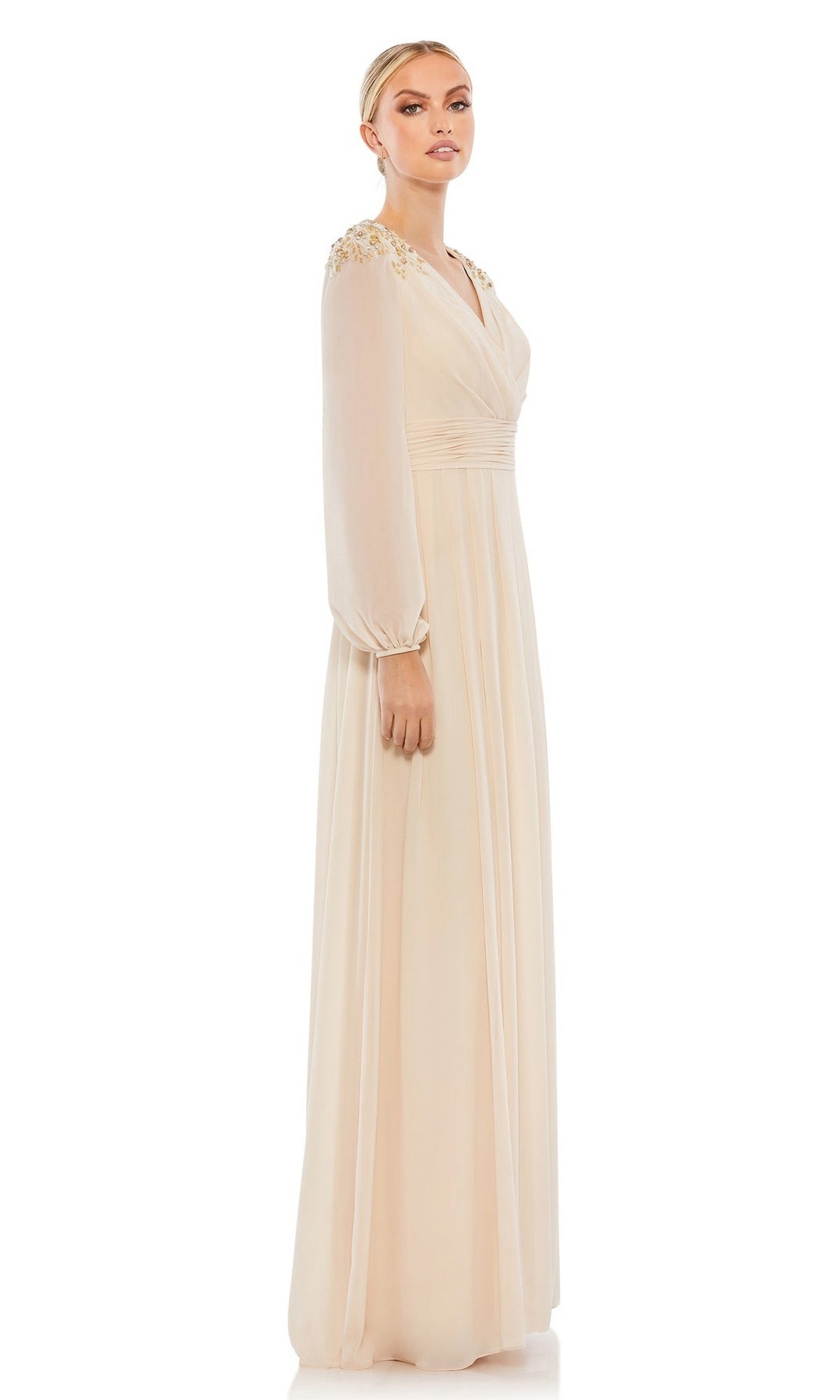 A woman models the Mac Duggal 55694, a long sleeve chiffon formal dress with decorative shoulders, in light beige against a plain white background, presenting an elegant mother of the bride look.