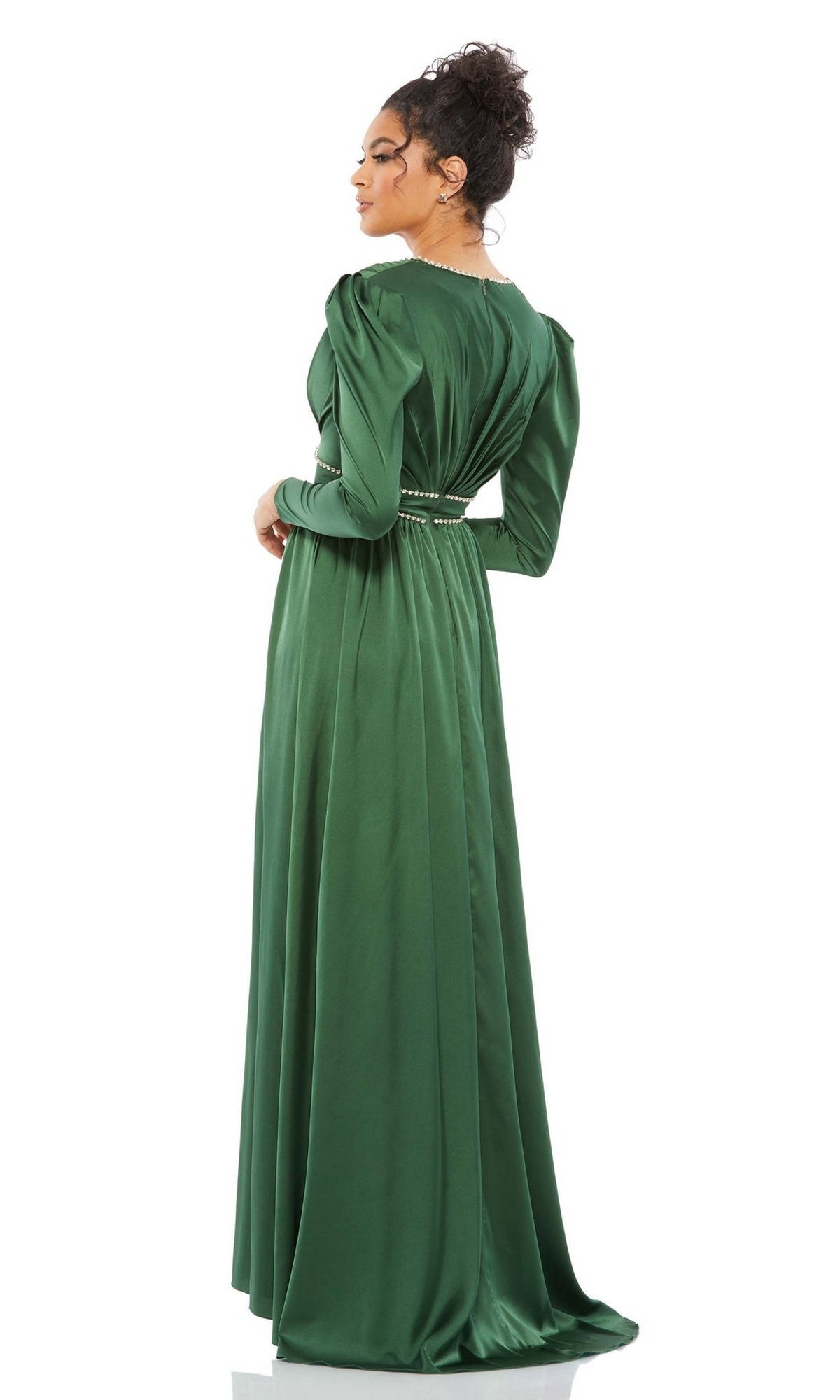 A woman stands facing away, looking over her shoulder, wearing the floor-length Long Formal Dress 55702 by Mac Duggal with long sleeves and a cinched waist.