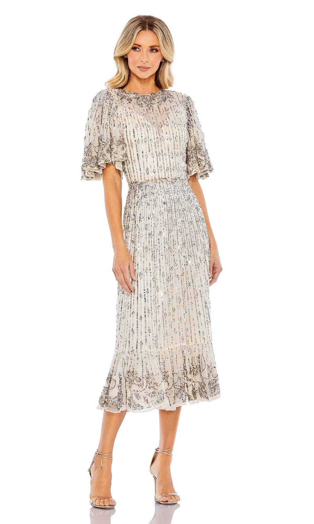 A woman wears the Mac Duggal 5579 Beaded Midi Semi-Formal Dress featuring short sleeves, a subtle metallic pattern, and a ruffled hem, styled with strappy heels for an elegant look.