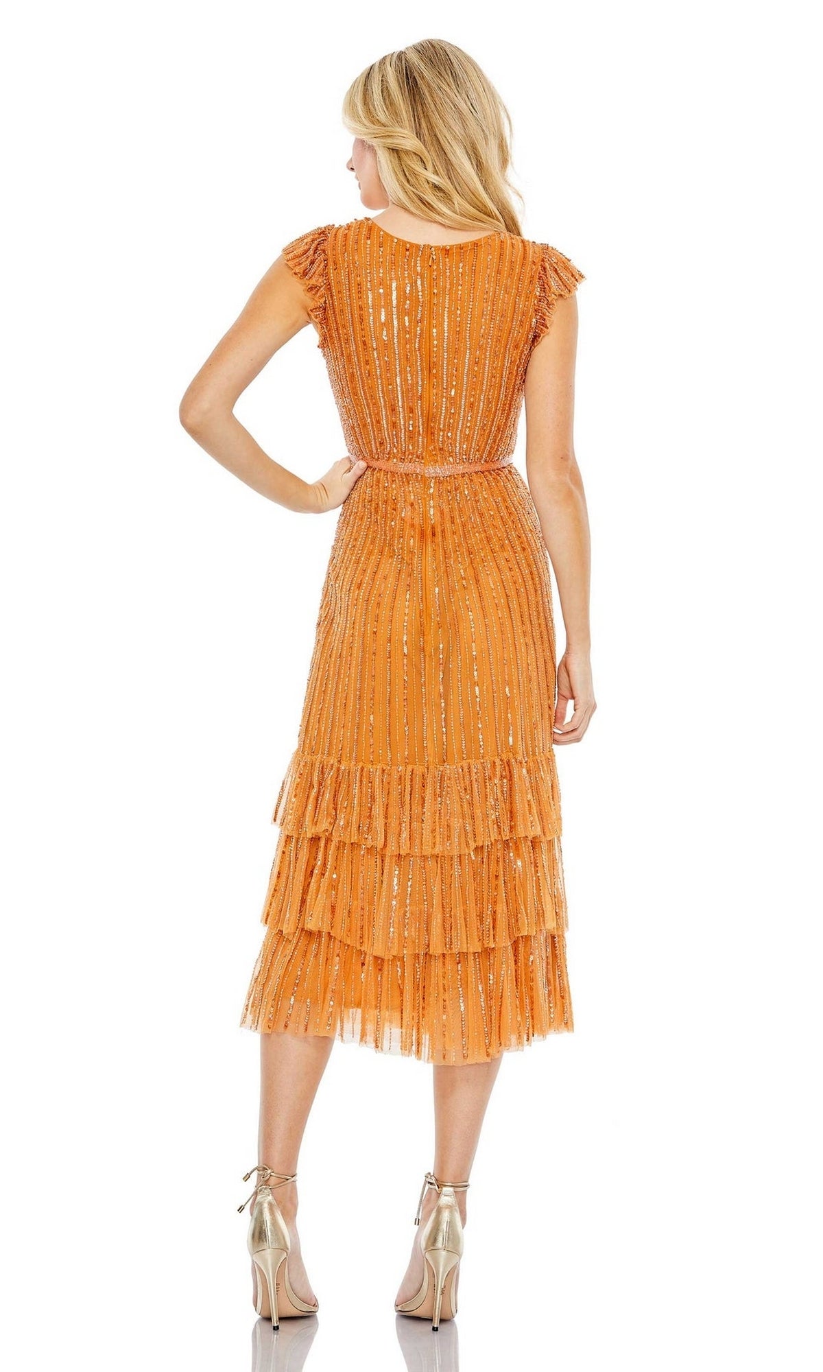 A woman faces away, wearing the Mac Duggal 5585 Cap-Sleeve Midi Party Dress in orange with layered pleats and metallic accents, styled with silver high heels.