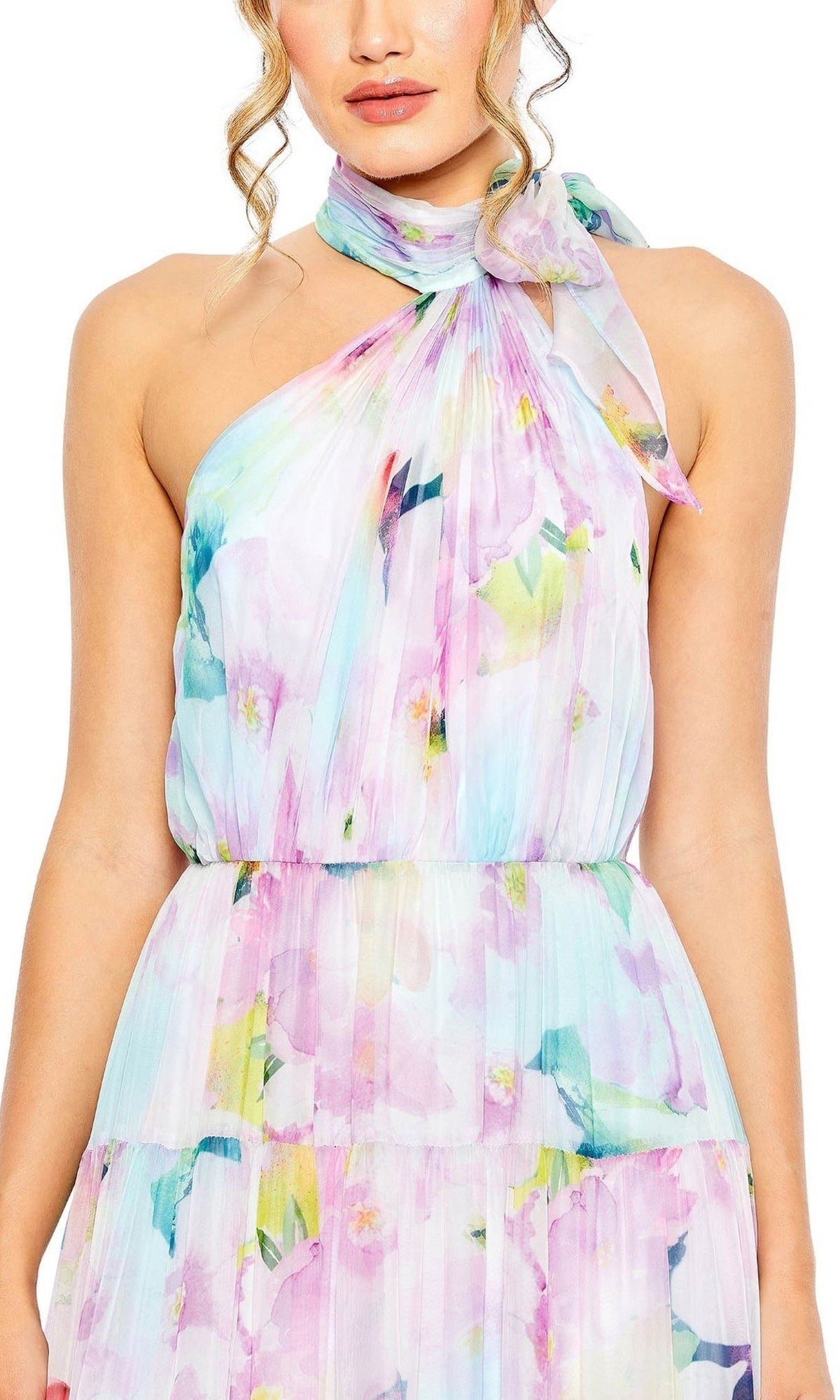 A woman wears the Long Formal Dress 55881 by Mac Duggal, a pastel halter-neck dress with tiered A-line silhouette, bow tie detail, and light pleated fabric in an abstract watercolor floral print.