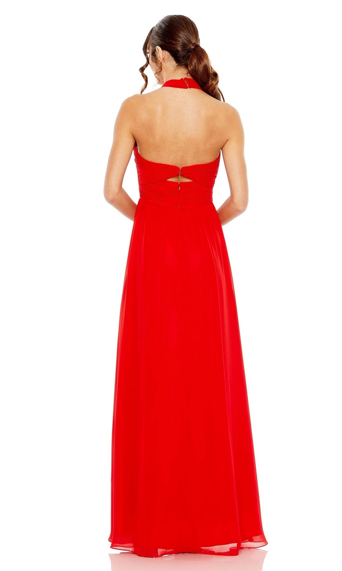 A woman stands against a white background wearing the Mac Duggal Long Formal Dress 55898, a floor-length, sleeveless red ruched halter neck gown with an open back and loose waves in her hair.