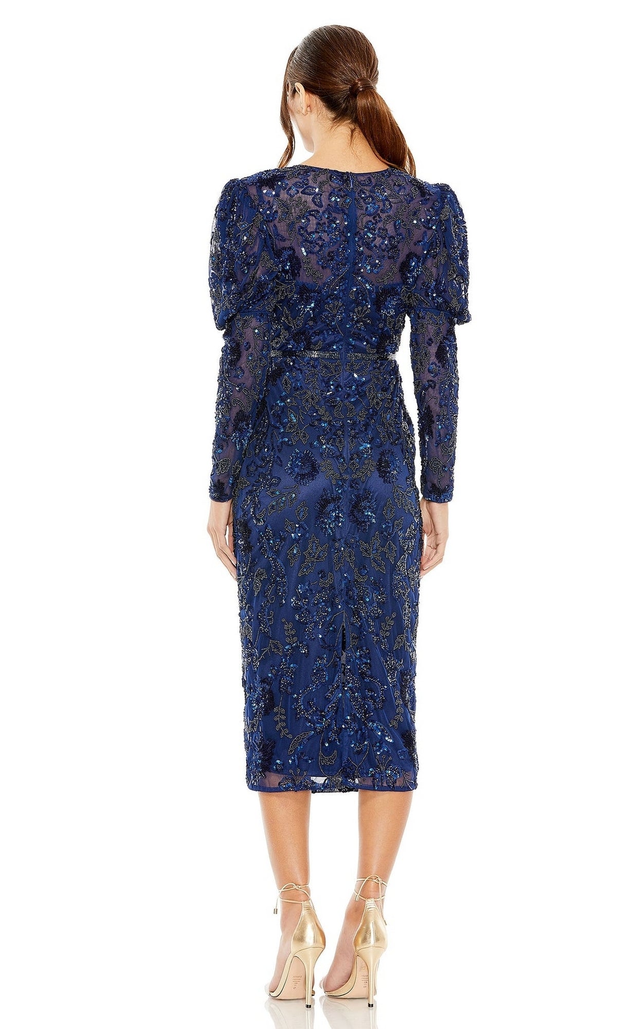 A woman stands with her back to the camera, wearing the Mac Duggal Short Semi-Formal Dress 5590 in dark blue, featuring long sleeves and a beaded waistband, paired with nude heels.