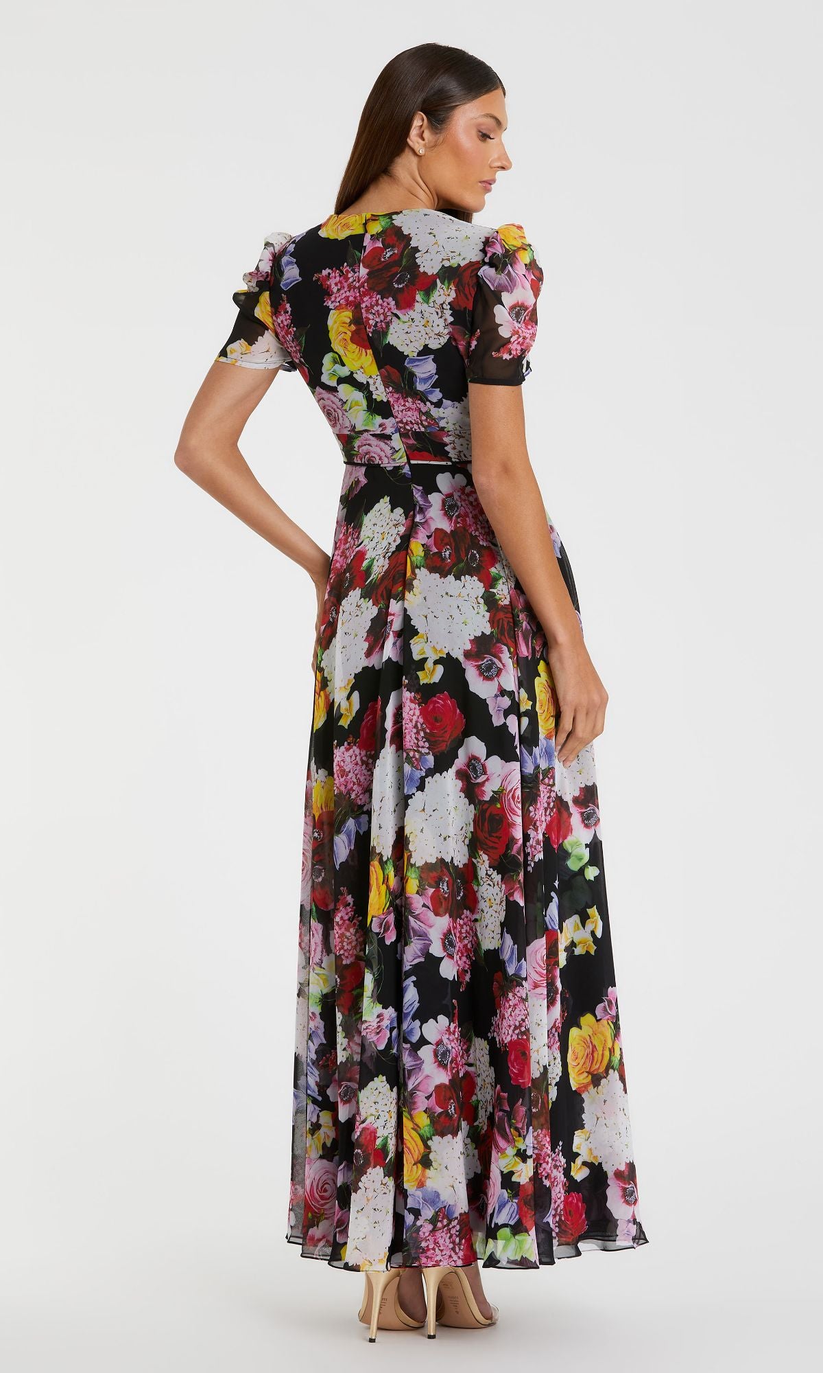 A woman is shown from the back wearing the Mac Duggal 55933 Short Sleeve Print Formal Dress with a fitted waist and flared skirt, styled with nude high heels.